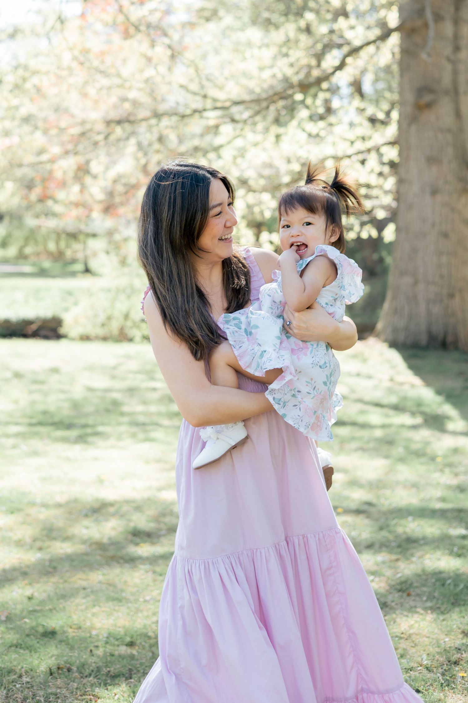 Mother holding and dancing with her daughter in a park outdoors during a family lifestyle session