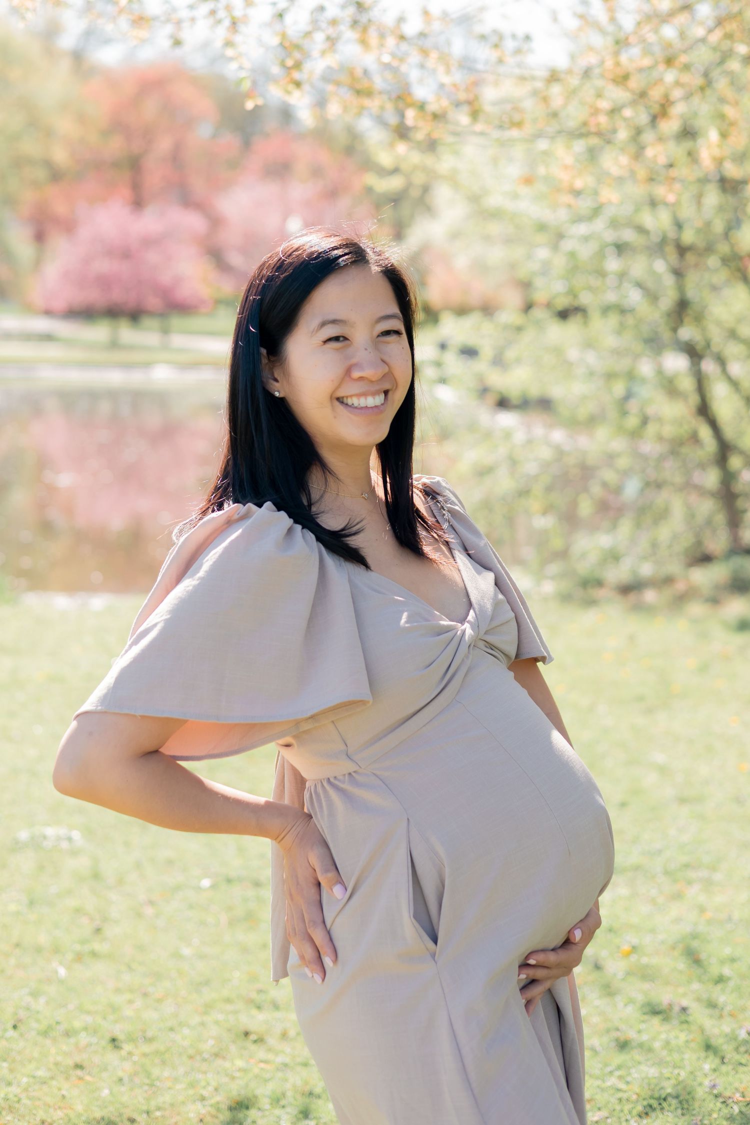 Pregnant mother embracing her baby bump in a park outdoors during a family lifestyle session
