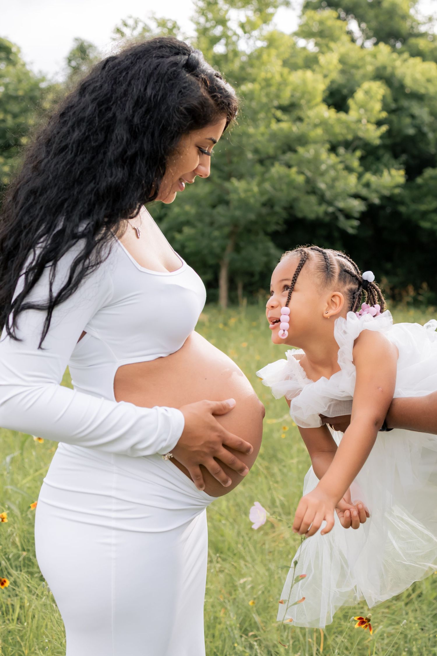 Daughter gazing up at her pregnant mom and smiling towards her belly
