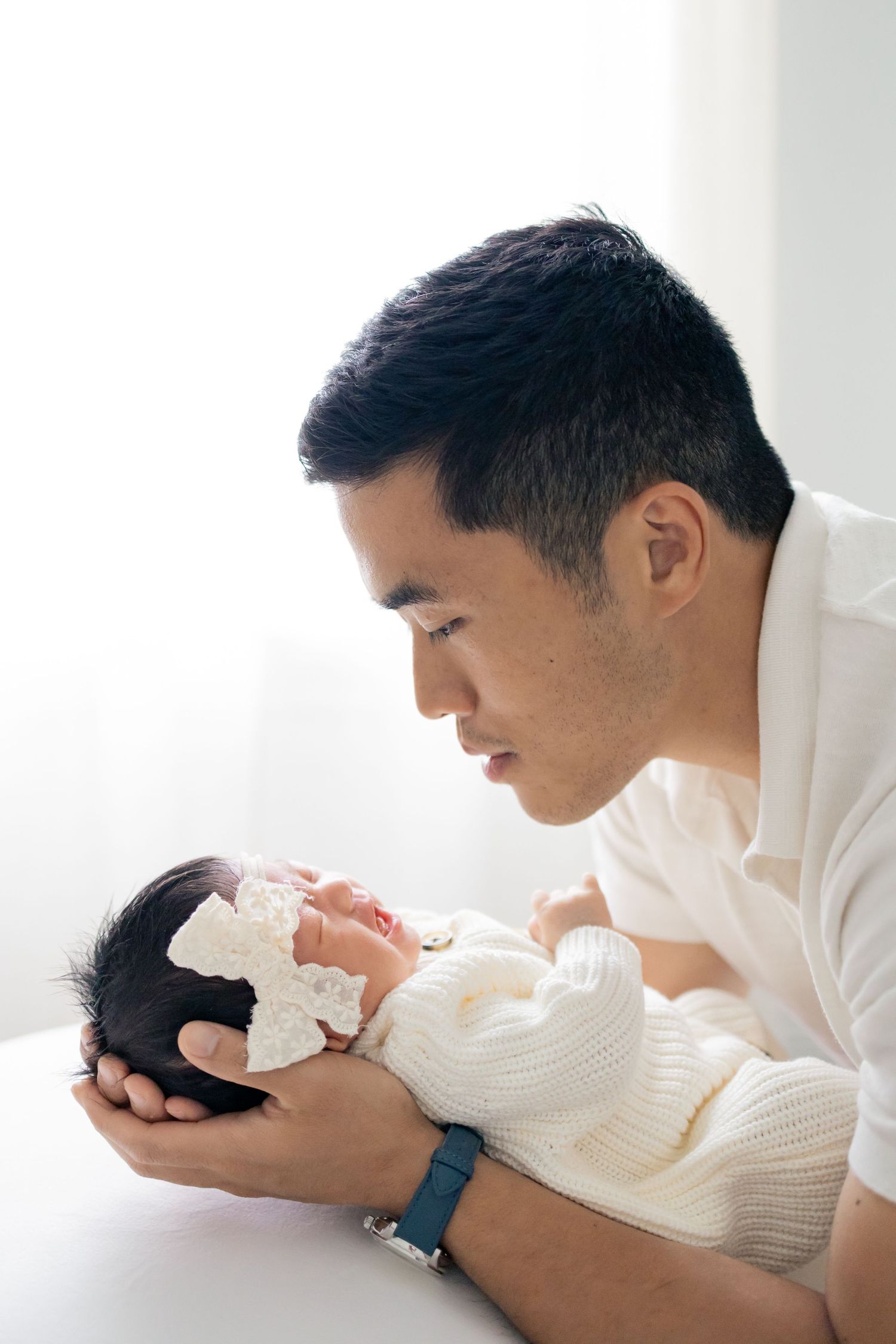Father cuddling and looking at newborn baby during a natural light lifestyle newborn session