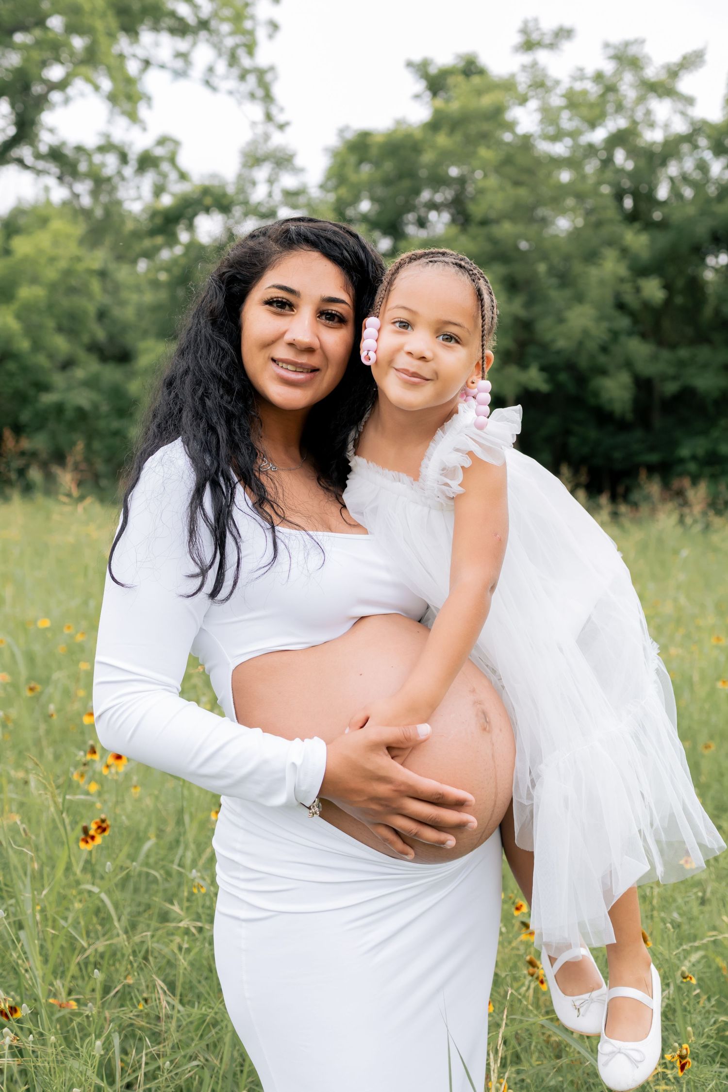 Pregnant mother holding her first daughter and smiling at a lifestyle family session