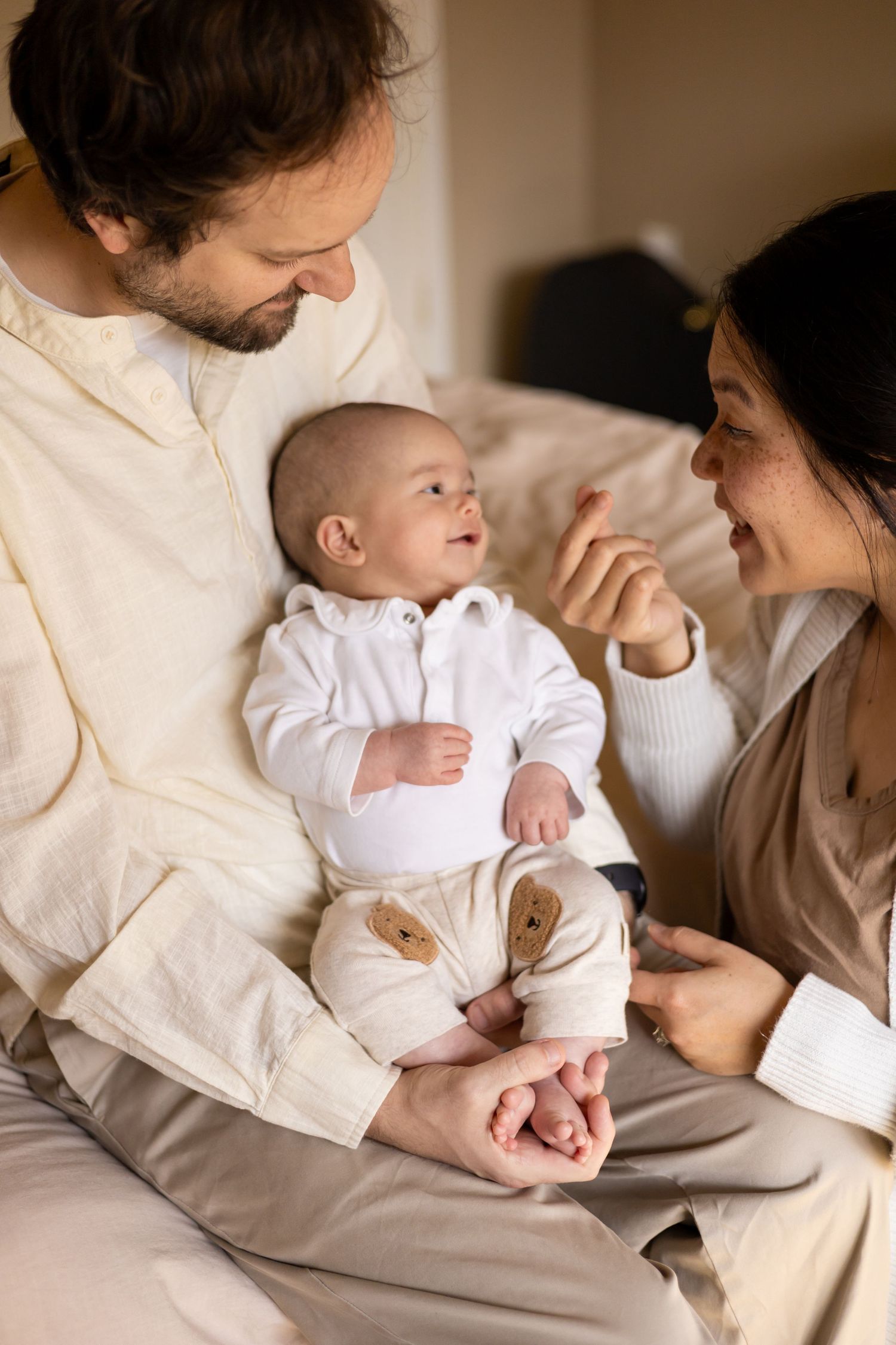 Parents laughing and playing with newborn baby during a lifestyle newborn session