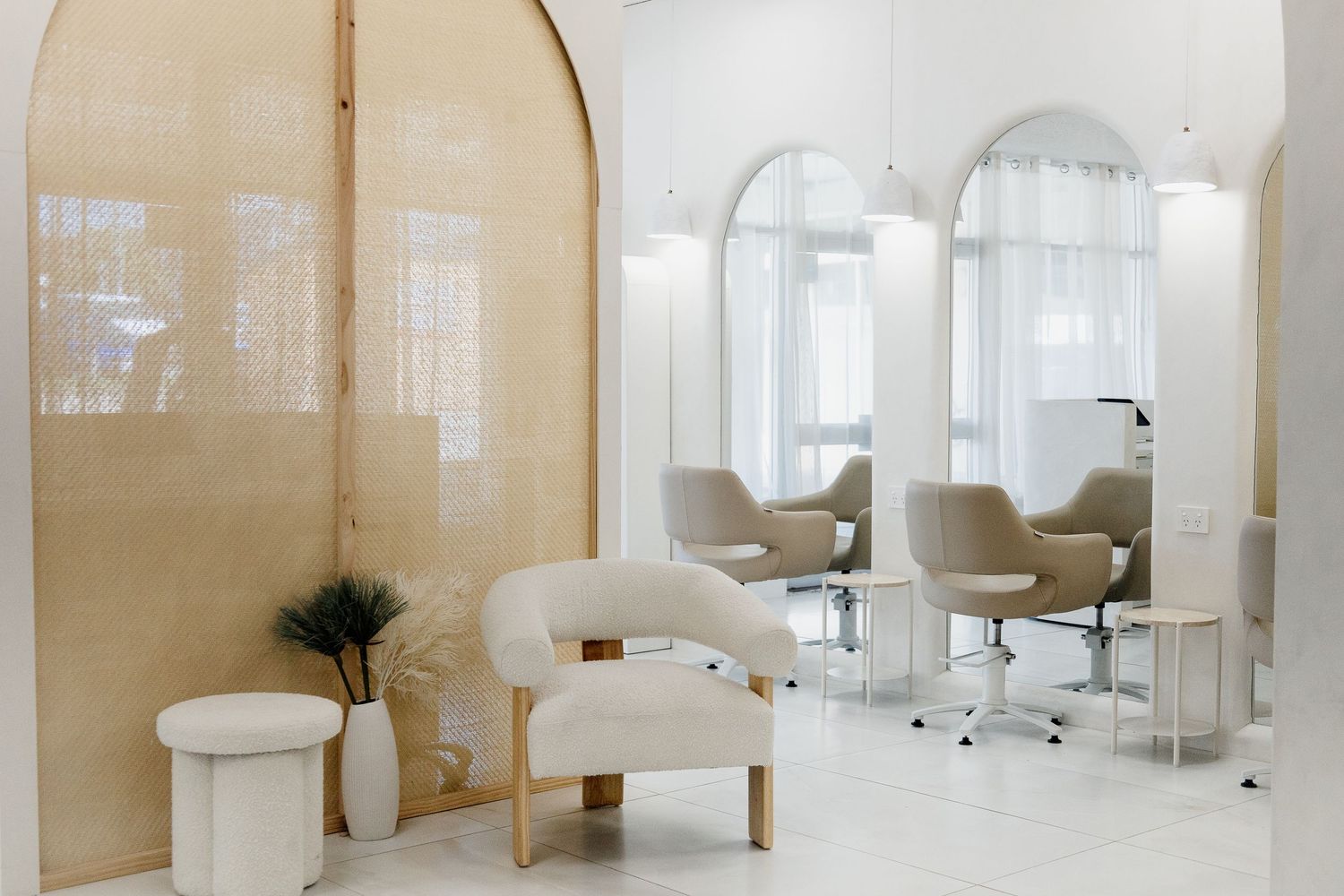 Elegant minimalist hair salon interior with arched gold panels, white chairs, and styling stations.