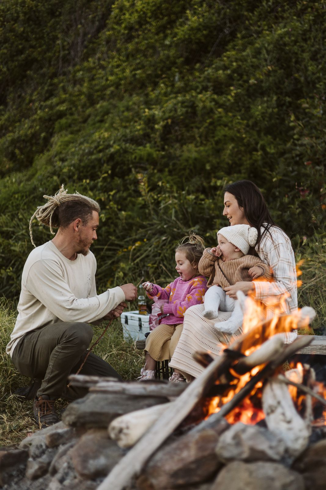 Family with two young children enjoying a campfire with marshmallows on the coast.