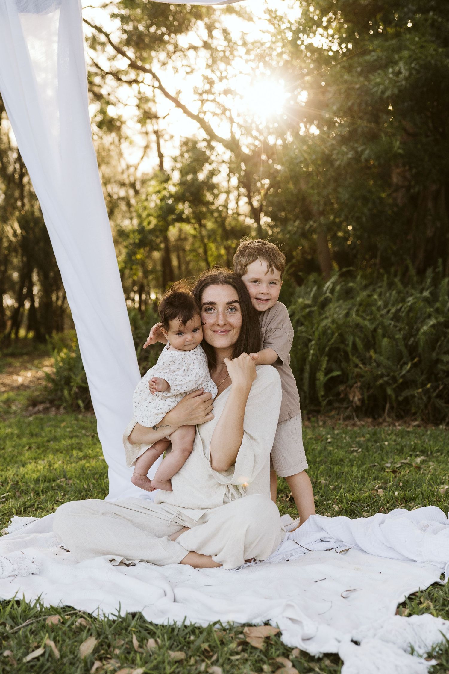Motherhood photoshoot at sunset with two children.