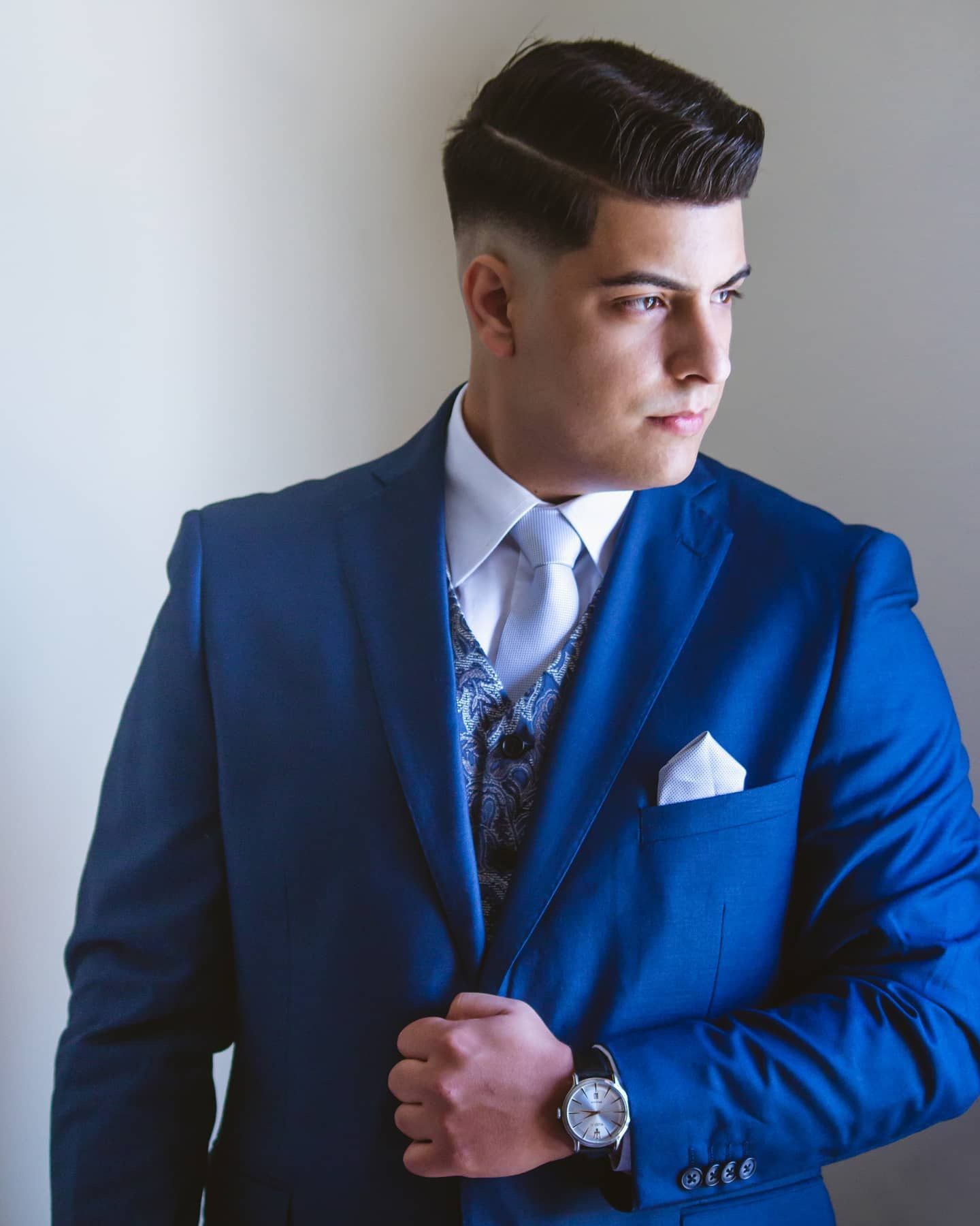 Stylish young groom poses in a royal blue three-piece suit with white pocket square.