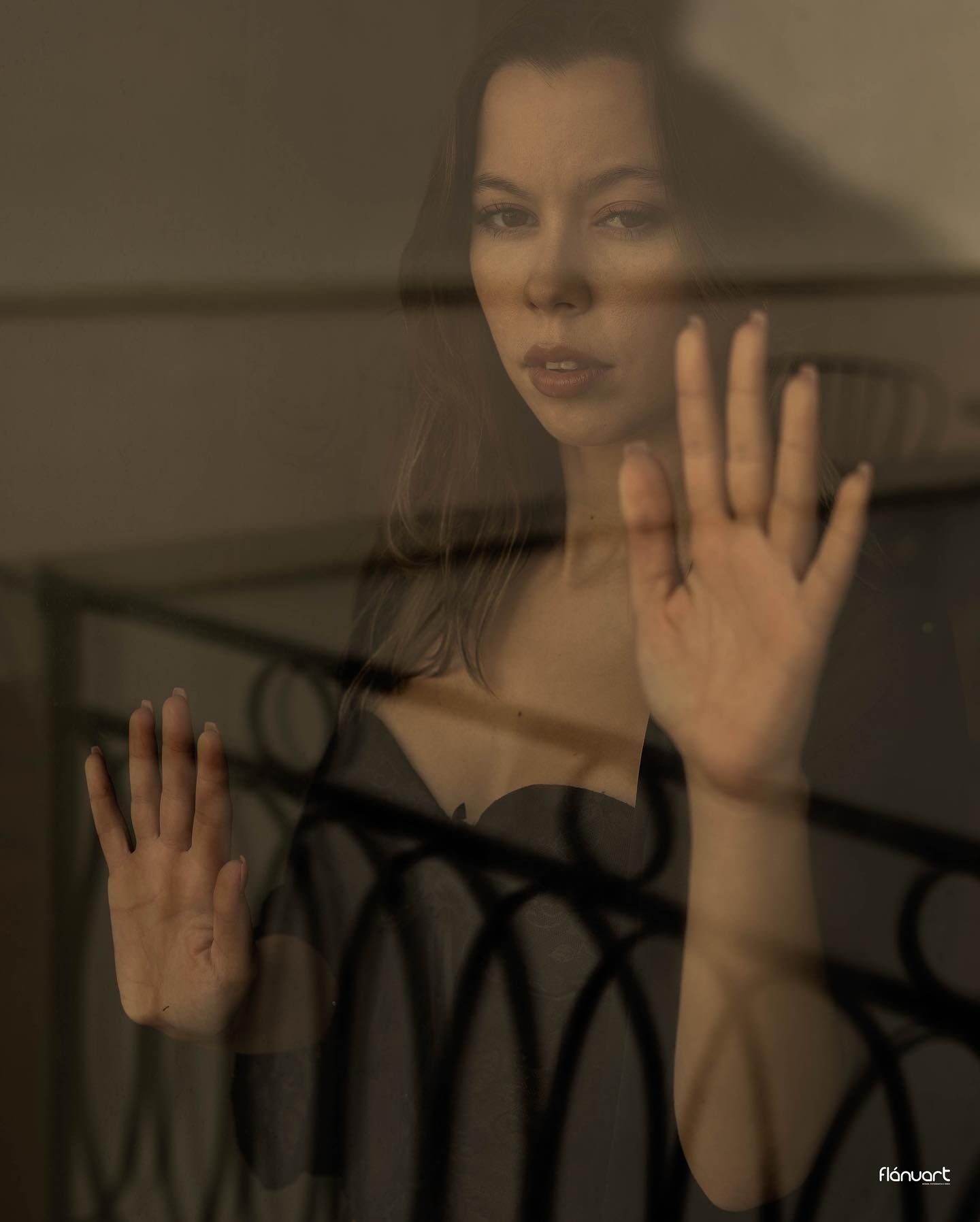Artistic photo of a woman pressing her hands against a glass window or door.