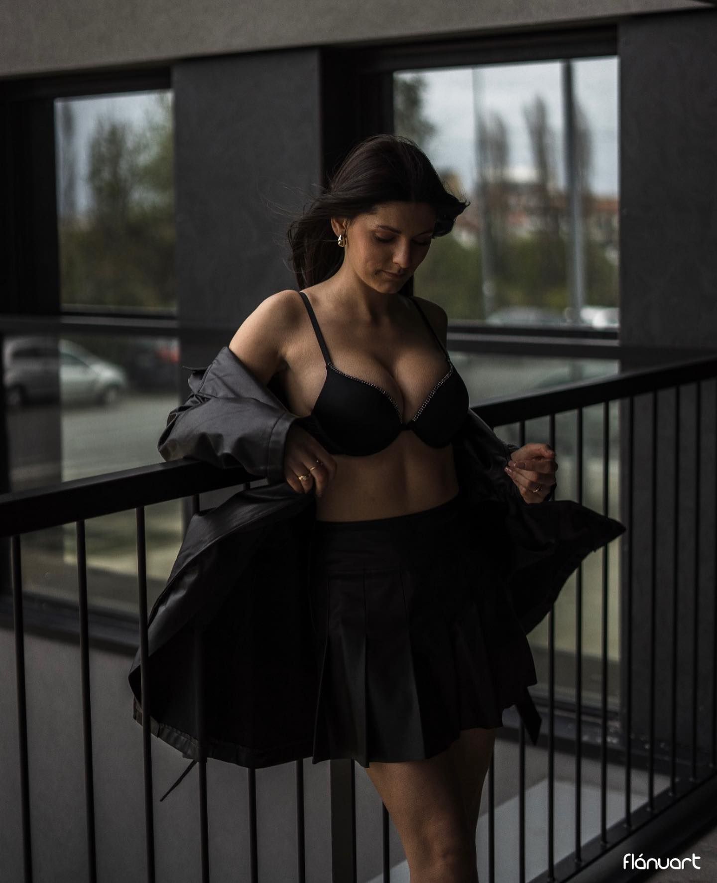 Woman in black bra and skirt on balcony with urban background.