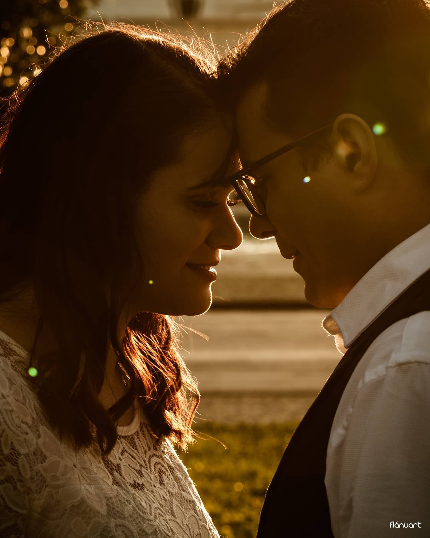 Romantic couple almost kissing in golden sunset backlight, man wearing glasses and white shirt.