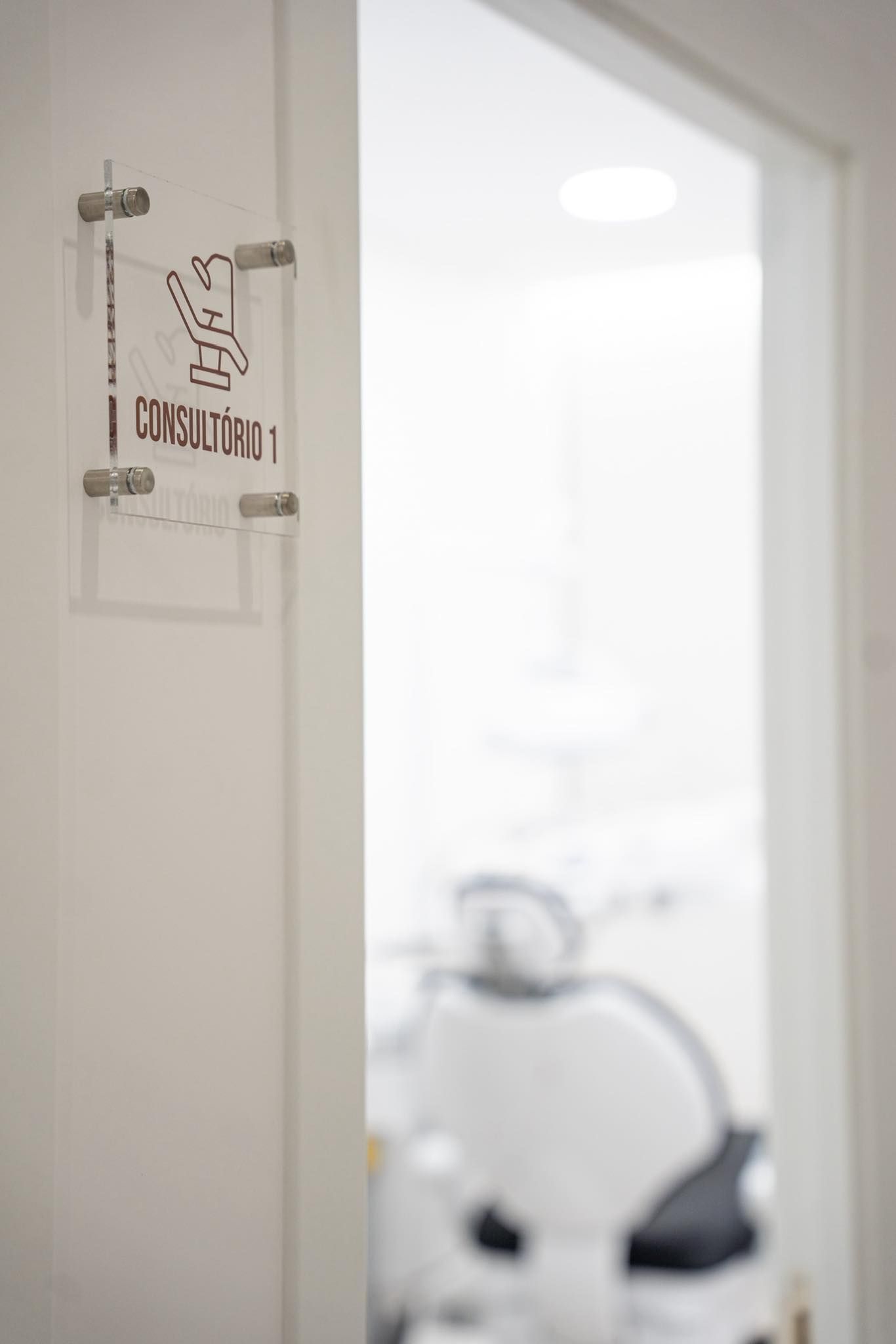 Consultorio 1 sign on white door leading to a bright modern dental treatment room.