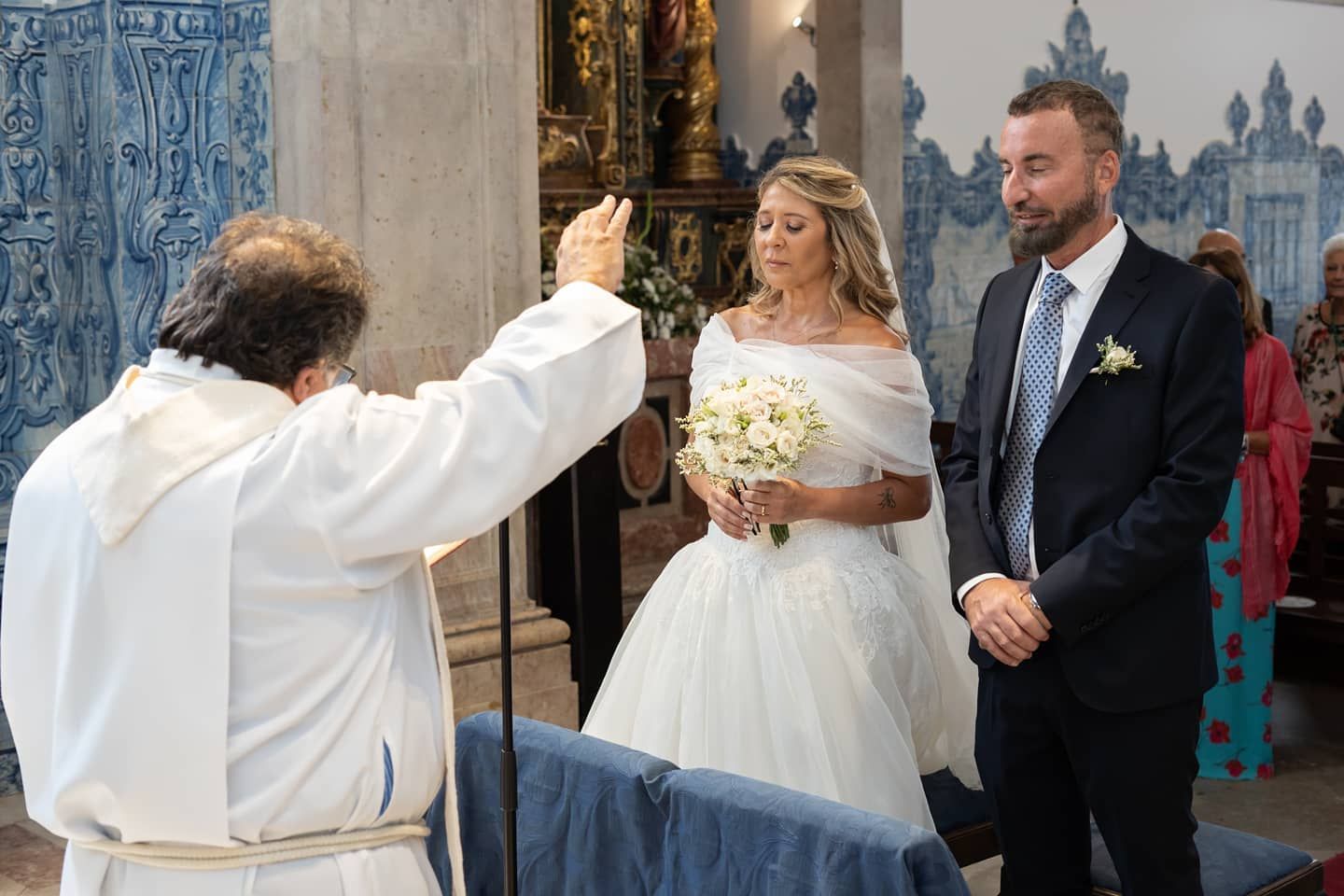 A priest blesses a bride and groom during a Catholic wedding ceremony in a church.