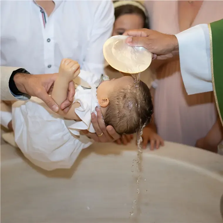 A Catholic priest pours holy water over a newborn baby's head during a baptism ceremony.