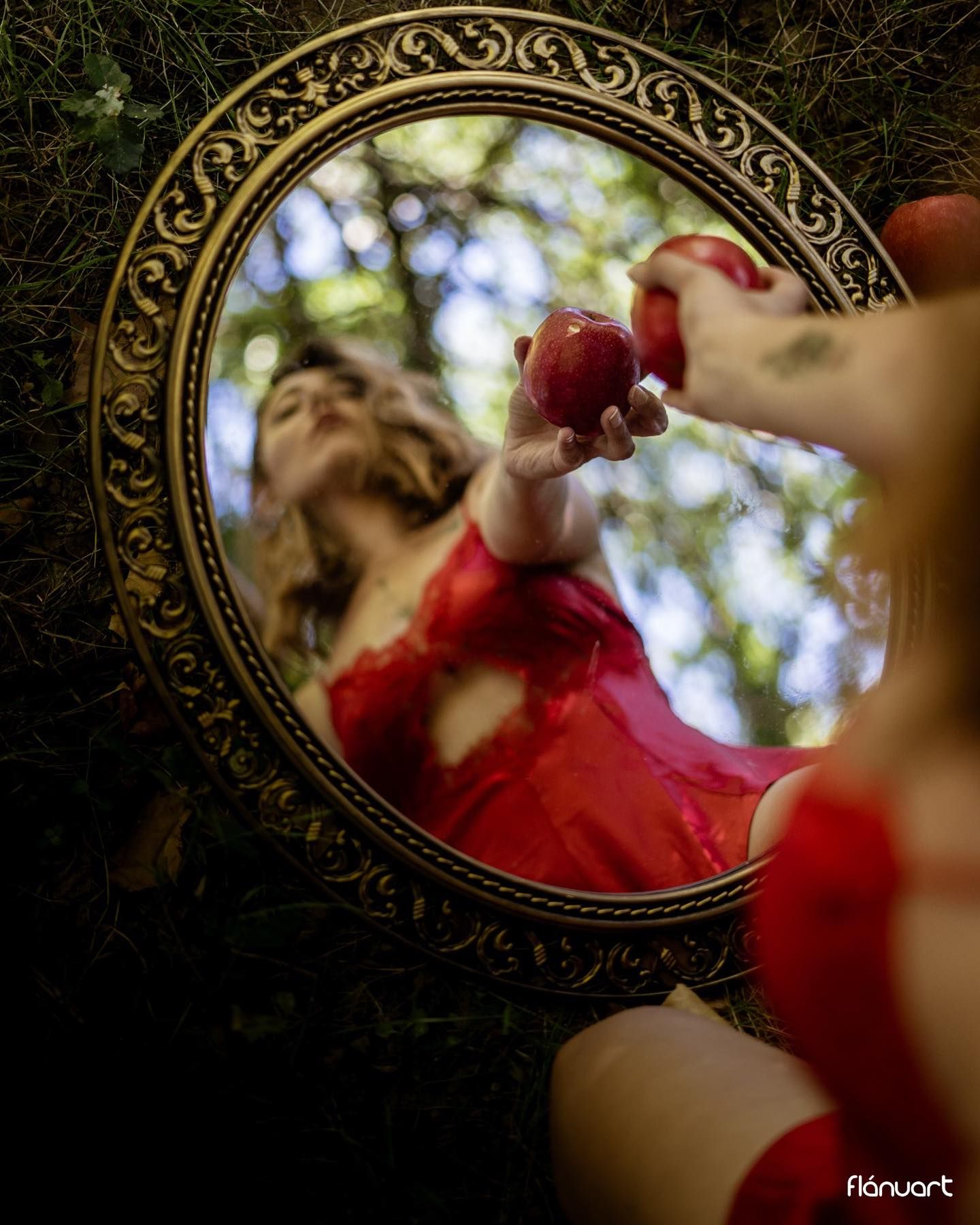 Creative mirror reflection of woman in red lingerie holding apple in forest.