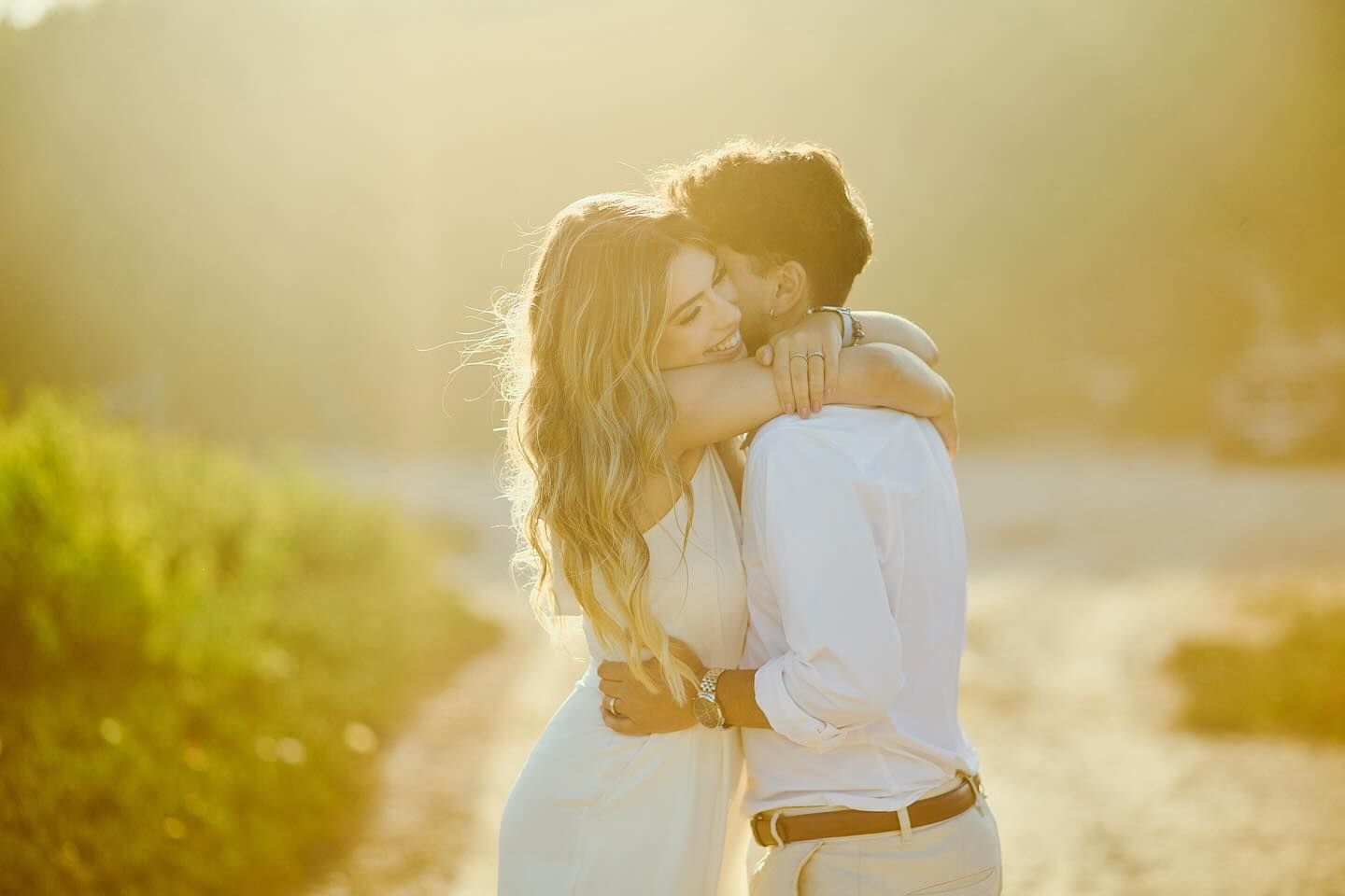Romantic couple kissing and embracing in warm golden sunlight in an outdoor setting.