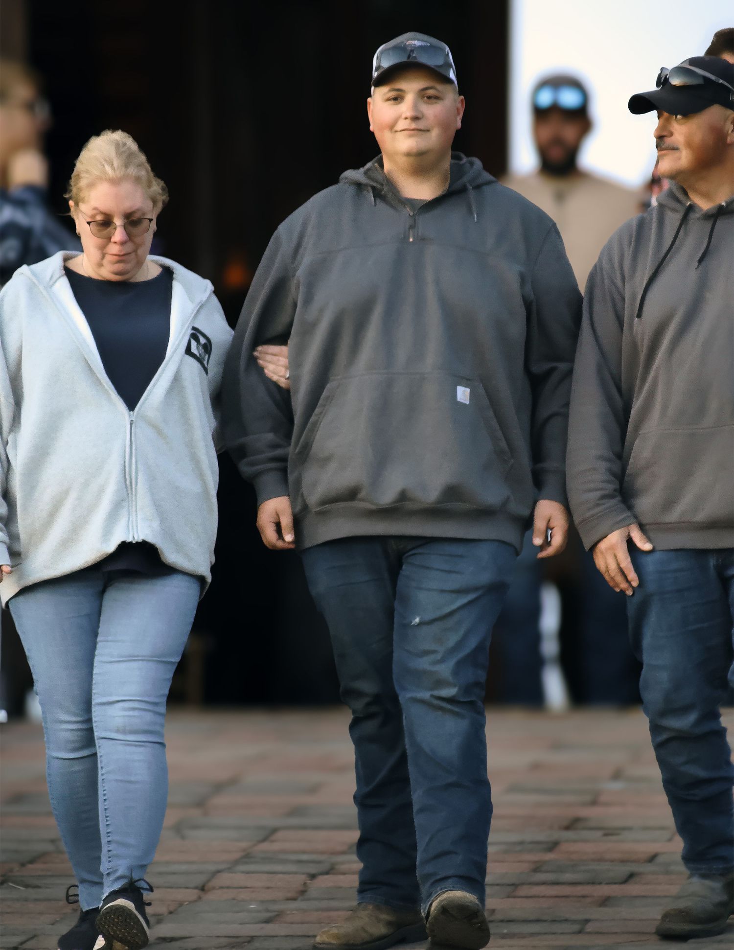 Group of people walking outdoors in casual hoodies and jeans.