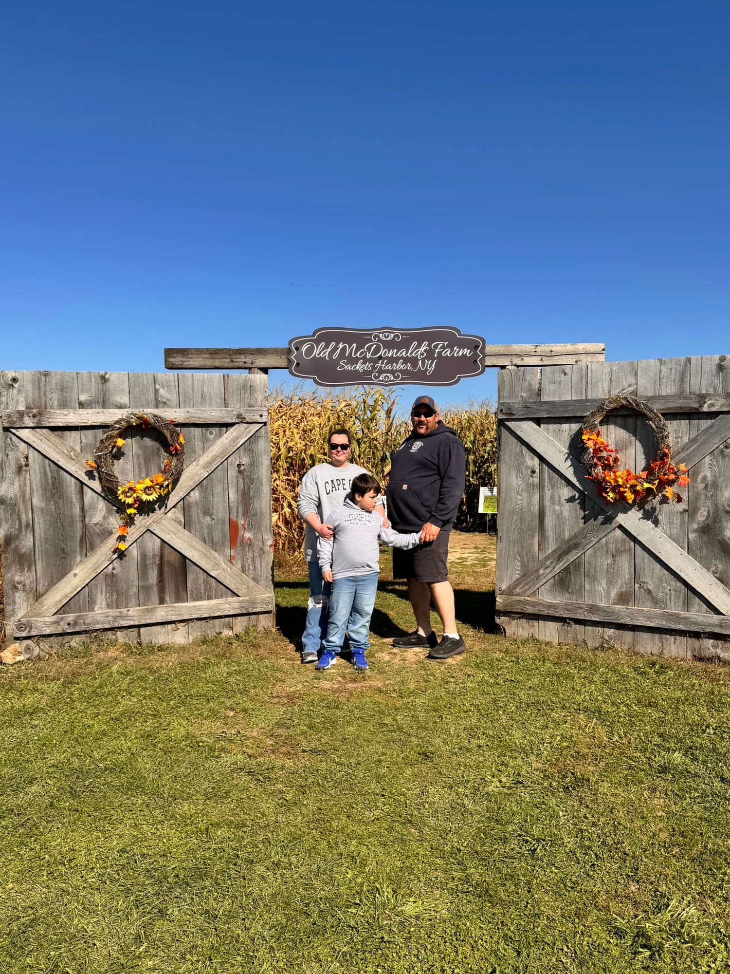Father and child pose at Old McDonald Farm entrance gate with fall harvest wreaths.
