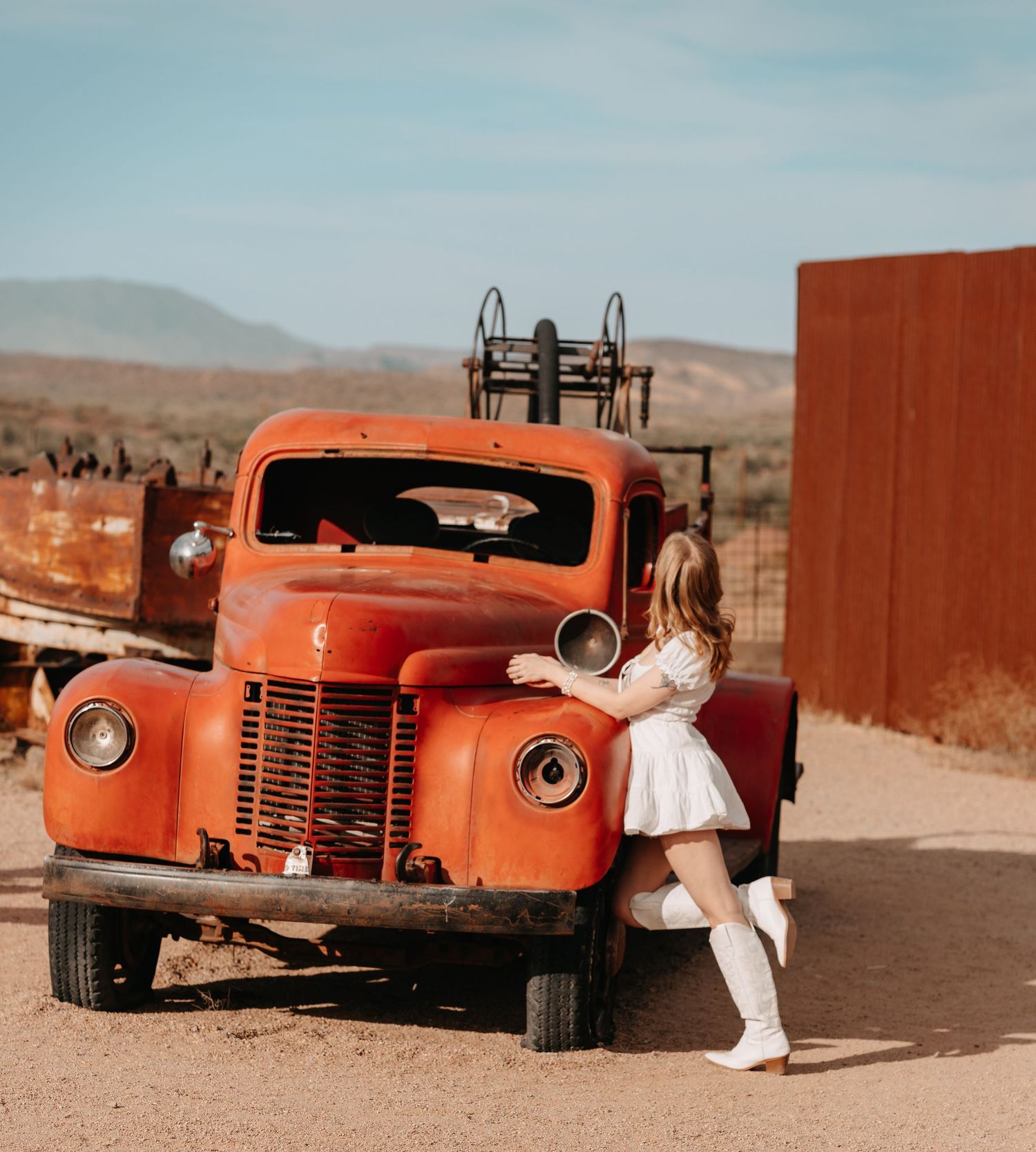 pretty red truck used in photos with girl in white dress and white cowboy boots leaning against truck in a dramatic style