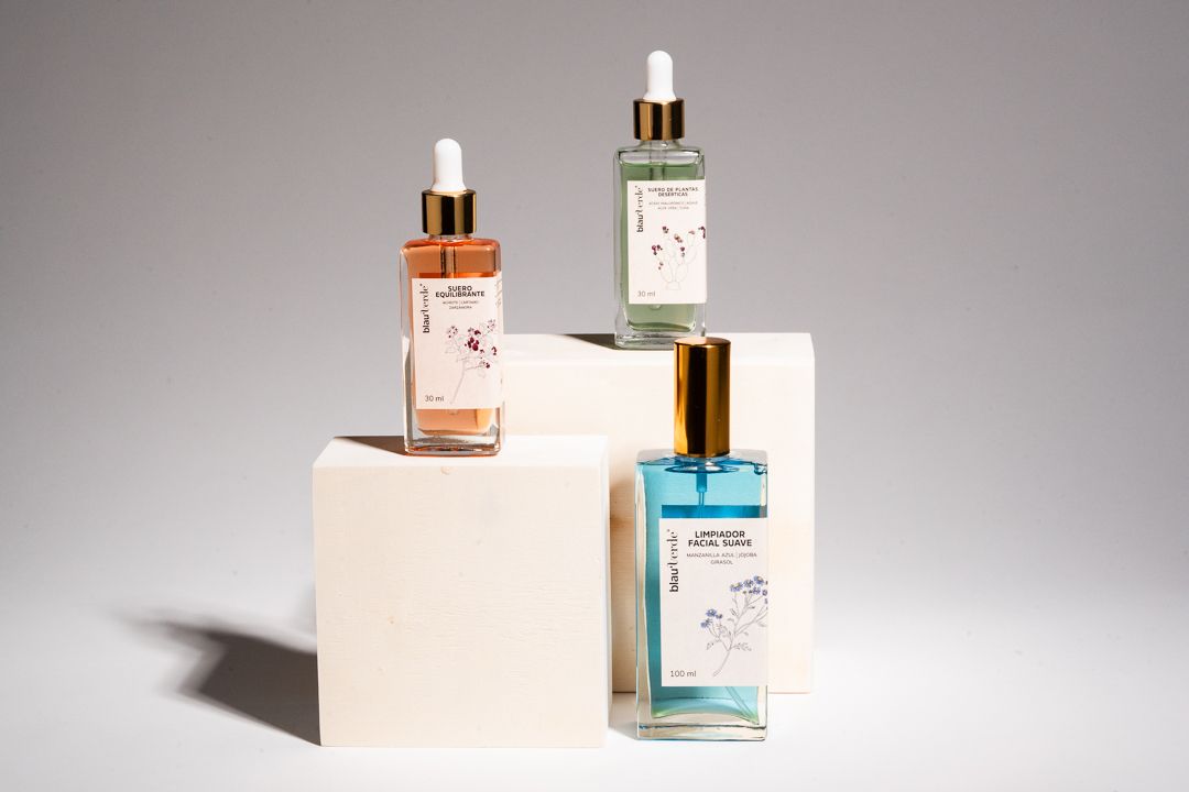 Three skincare serum bottles displayed on white geometric pedestals against a neutral gray background.