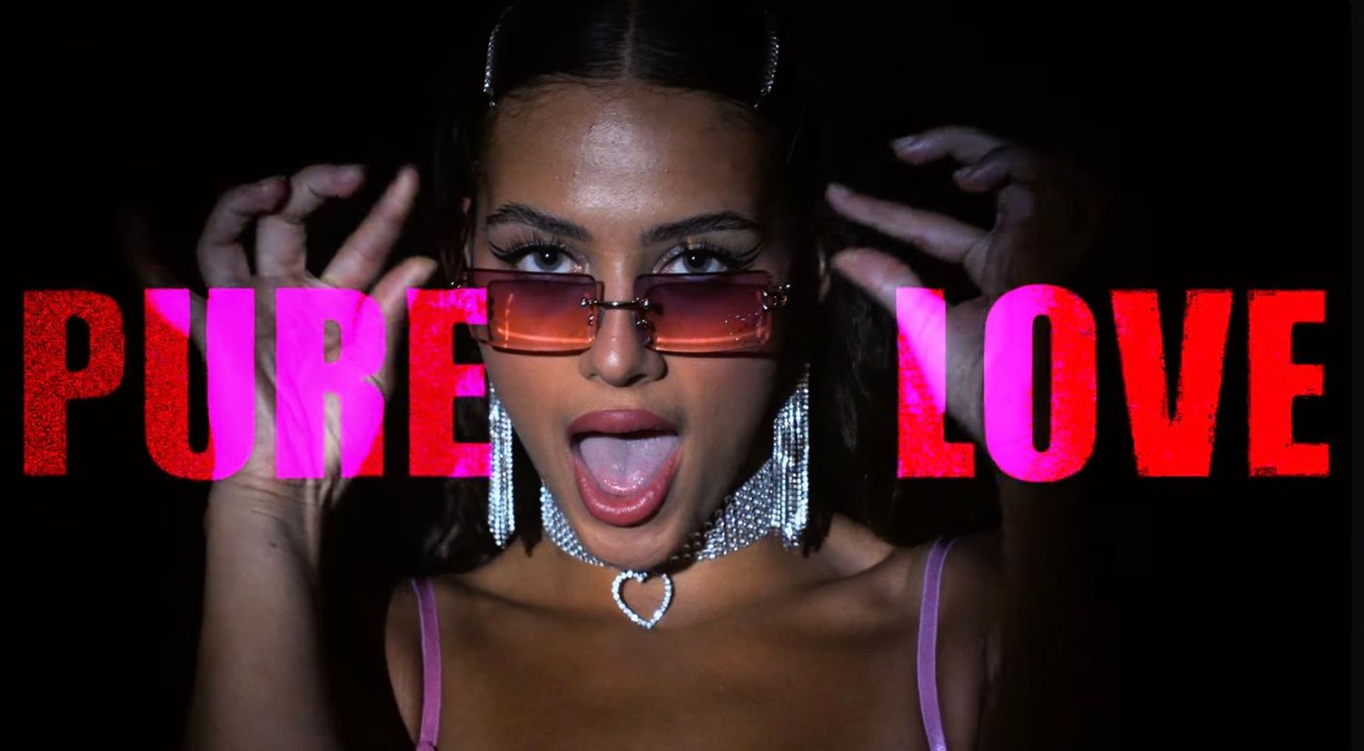Young woman in pink top and red sunglasses poses dramatically with 