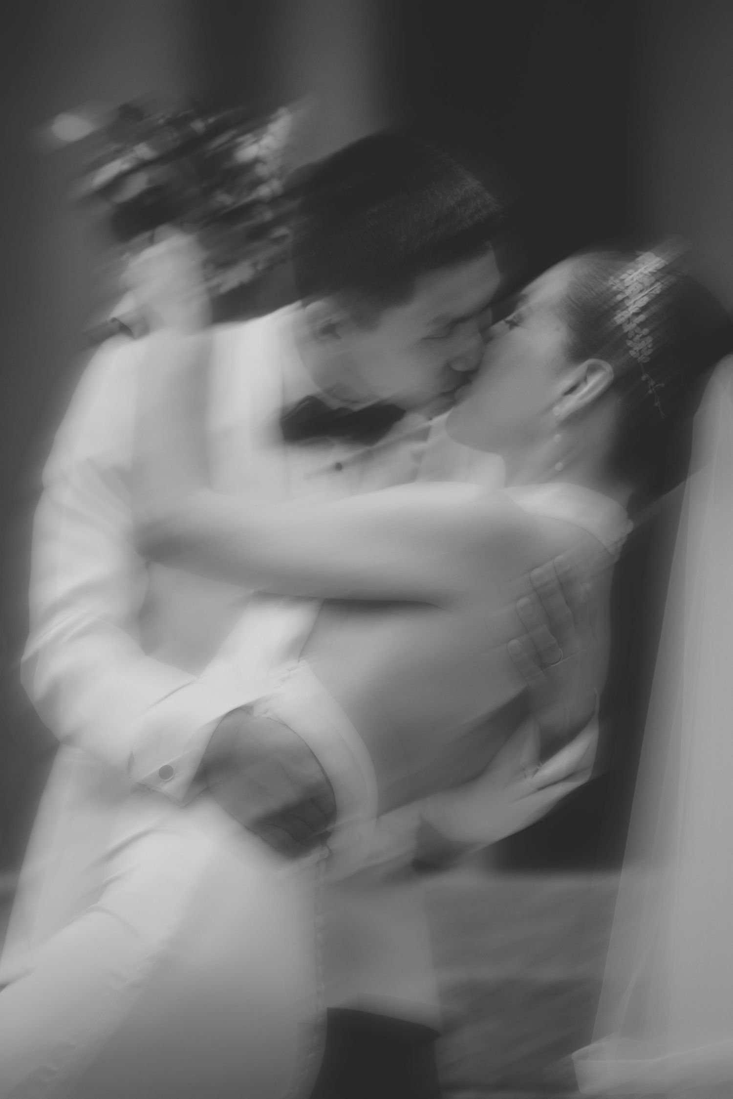 Blurred black and white photo of a bride and groom sharing a romantic embrace during their wedding dance.