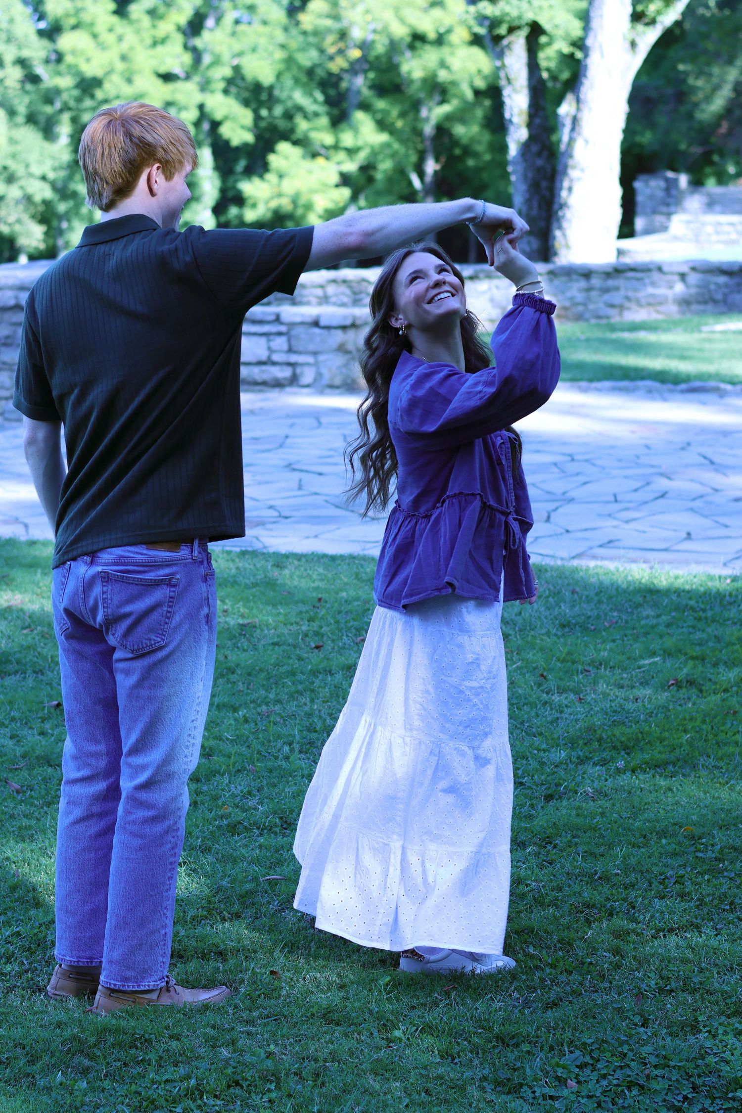 Couple dancing together on stone patio with green landscape backdrop.