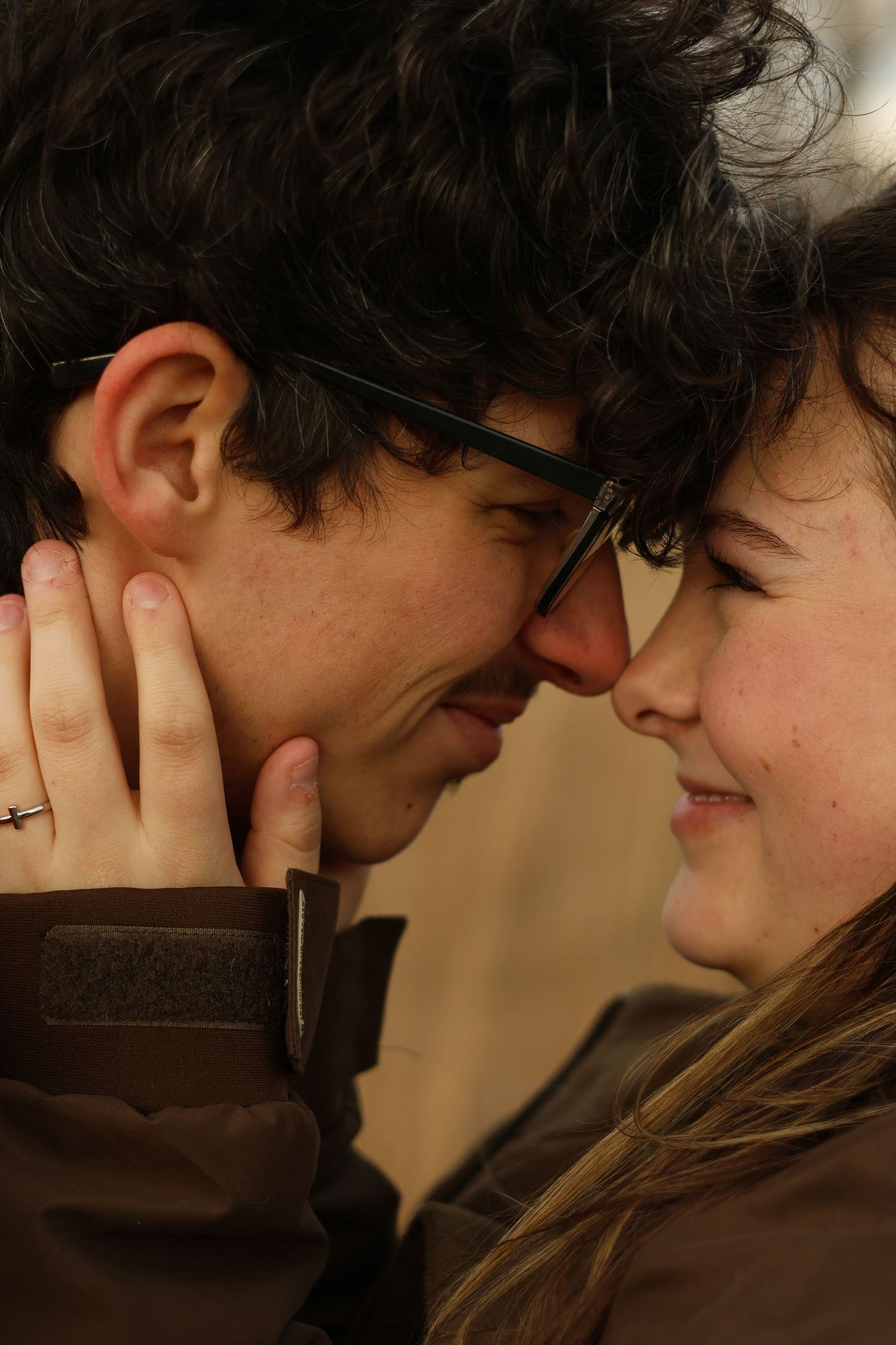 A tender romantic moment between two people in glasses sharing an intimate close up embrace.