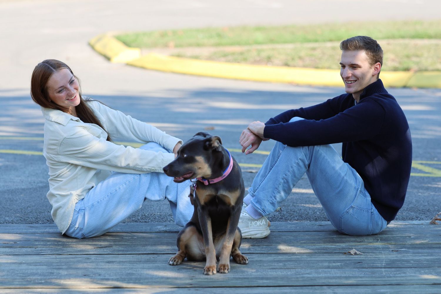 Couple relaxing on pavement with their small black and tan dog.