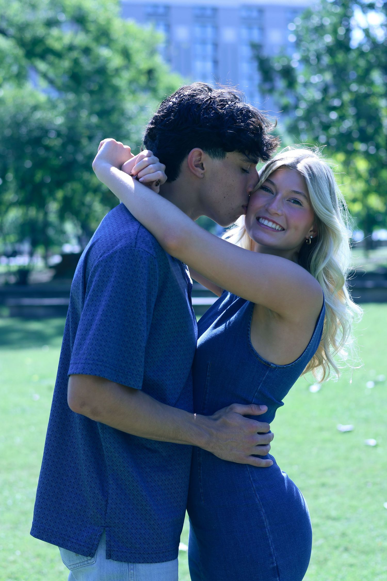 A happy couple shares an intimate moment while embracing in a sunny park.