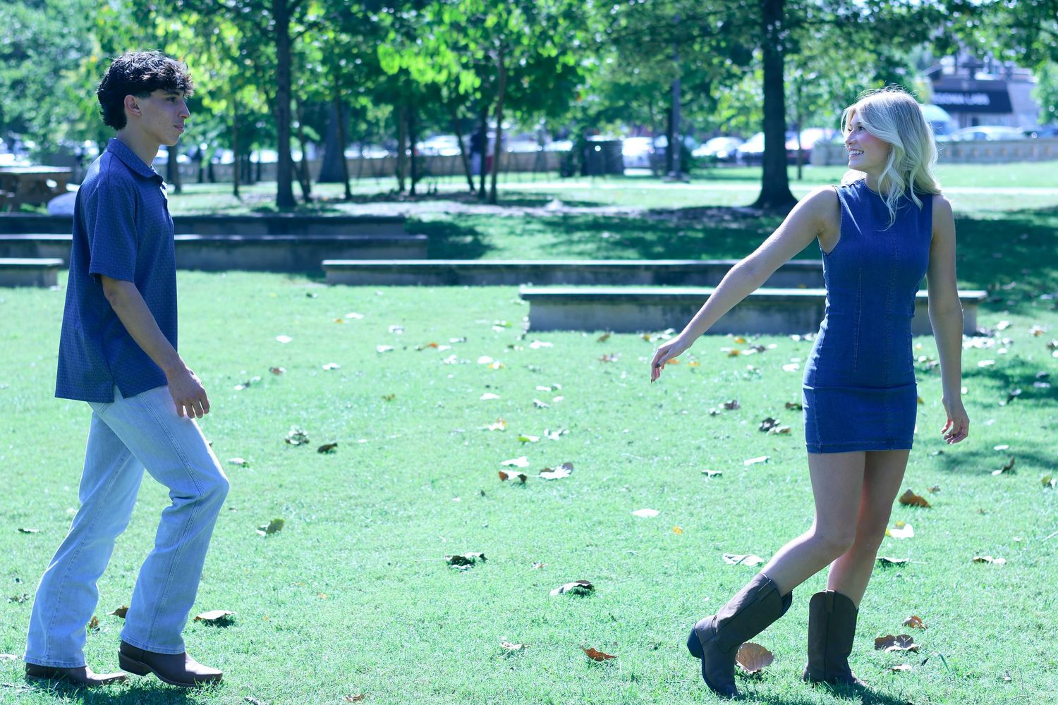 Couple in blue and white outfits walking together in sunny park.