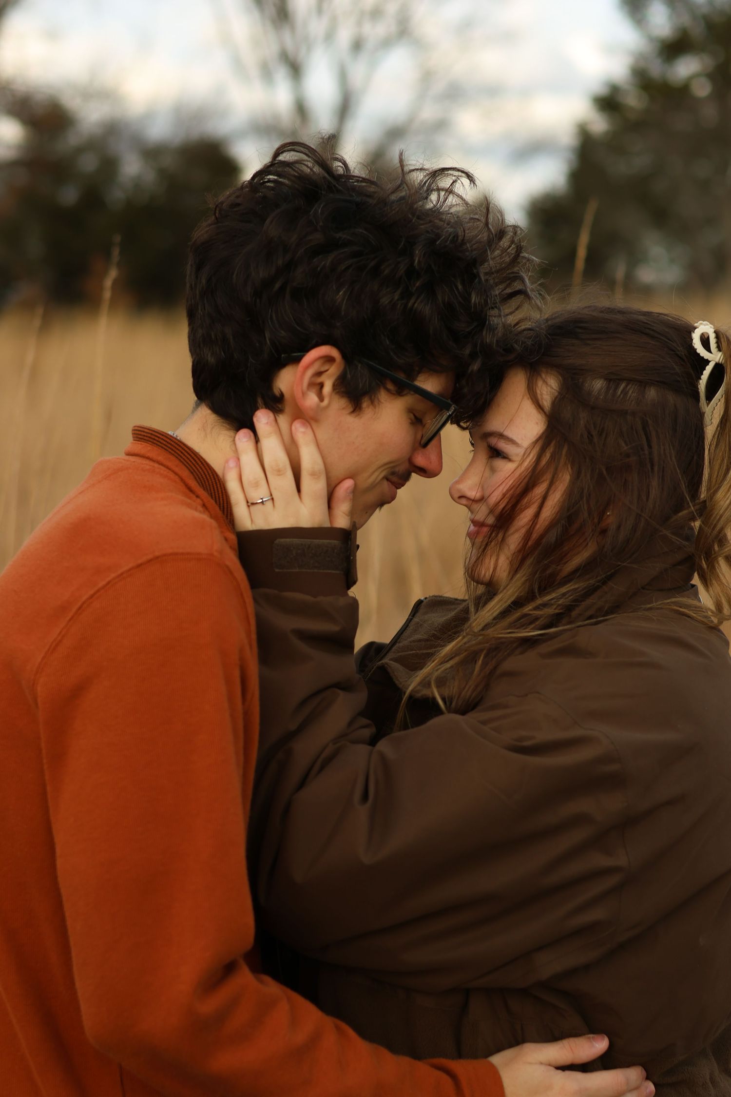 A tender romantic moment between a couple embracing in a field during golden hour.