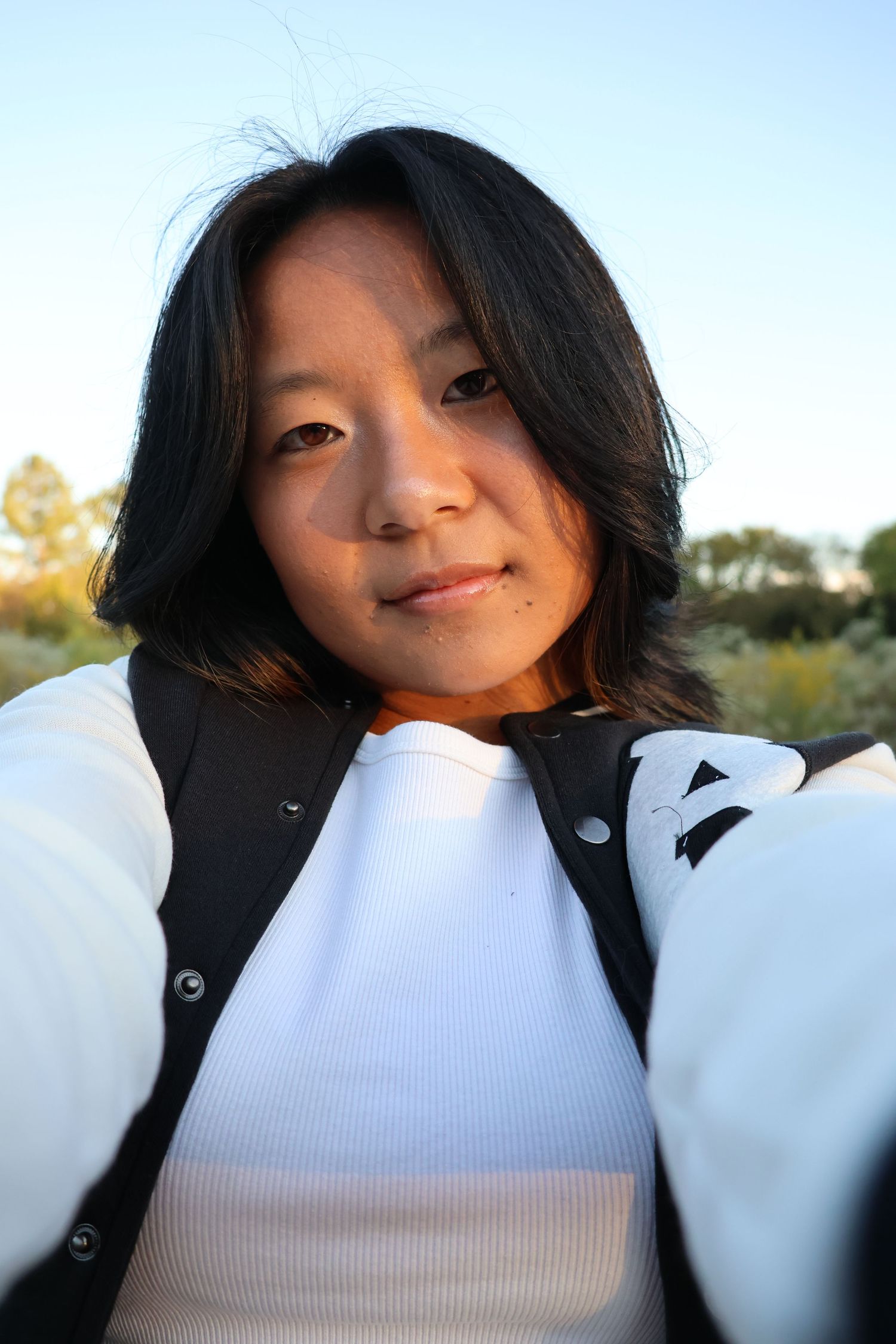 A series of four selfie photos showing someone wearing a white turtleneck sweater and black jacket outdoors.