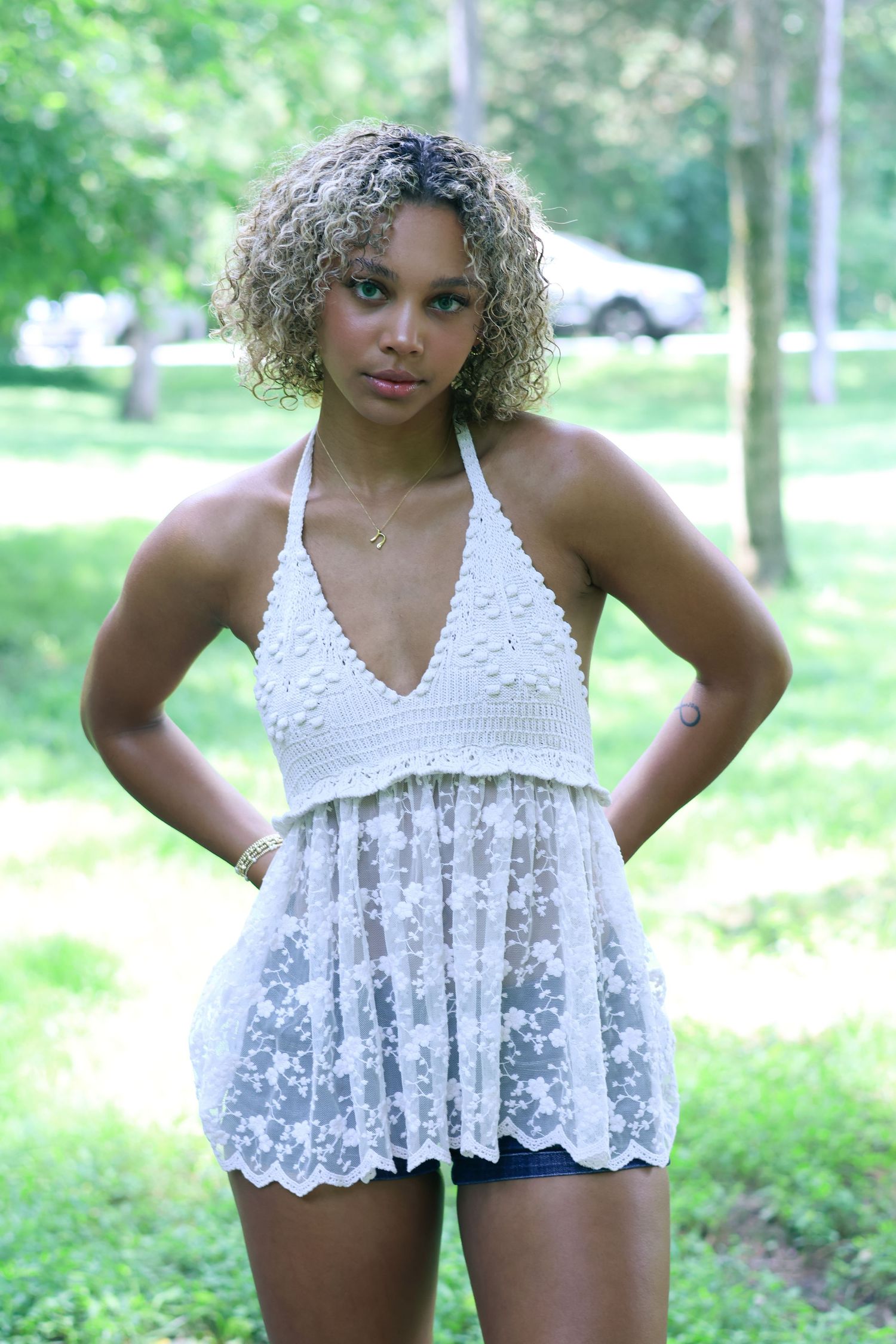 Summer portrait in white lace dress against lush green outdoor background.