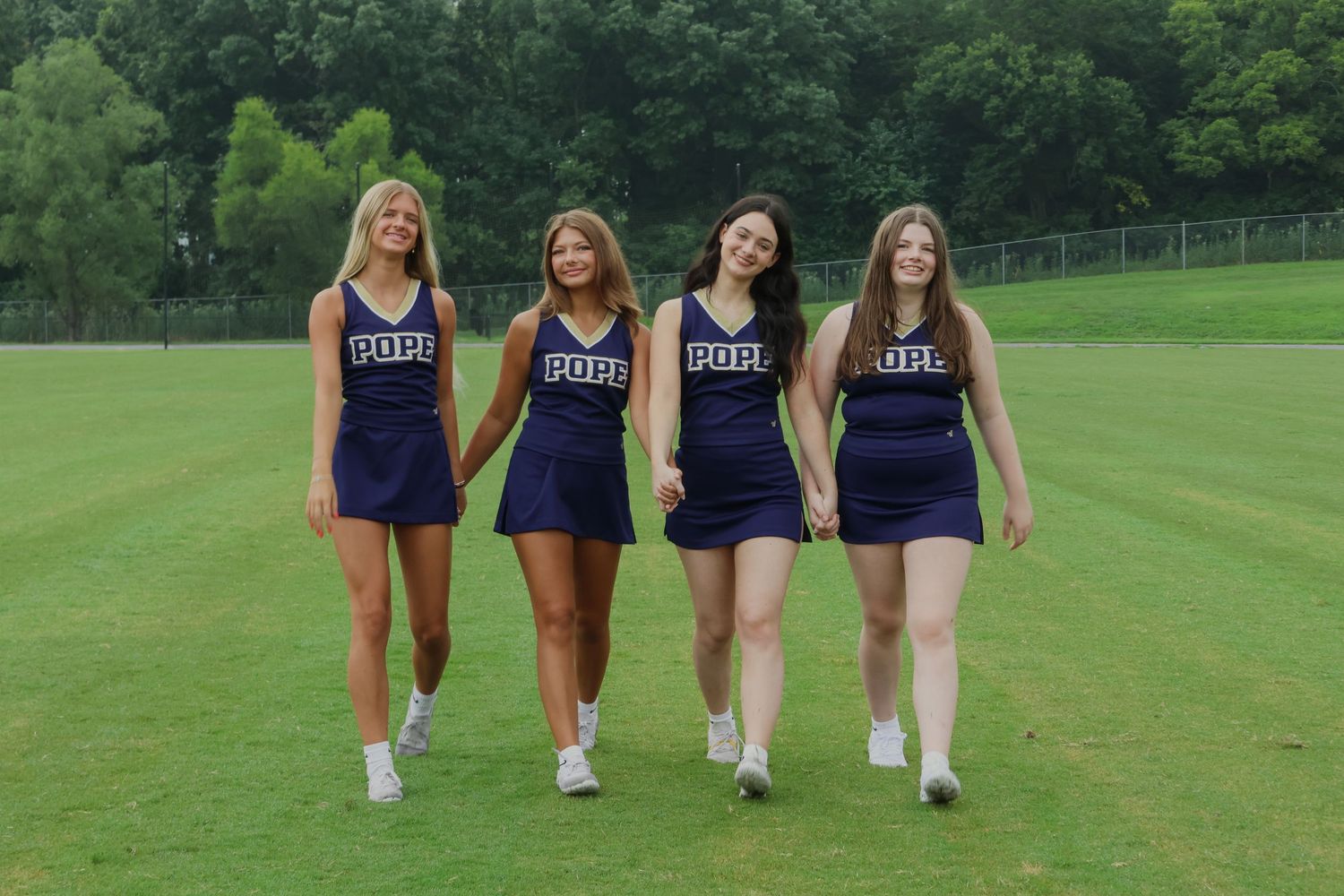 Digital photograph of 4 cheerleaders holding hands.