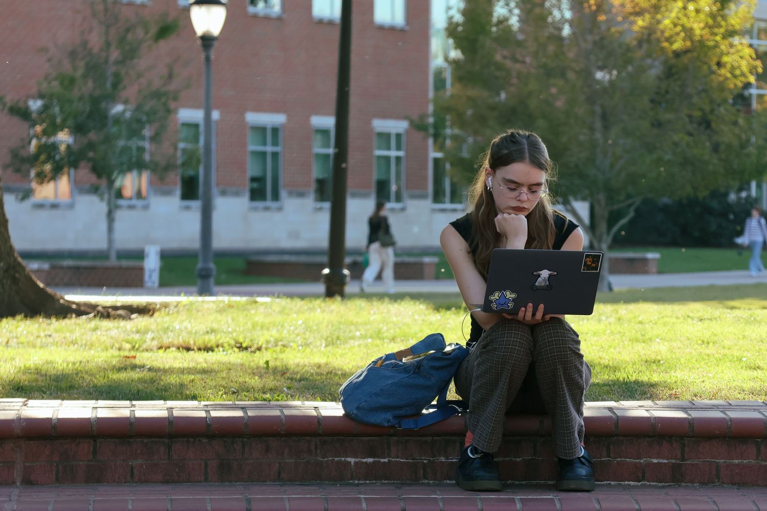 Digital photograph of a young adult (female) on her laptop outside.