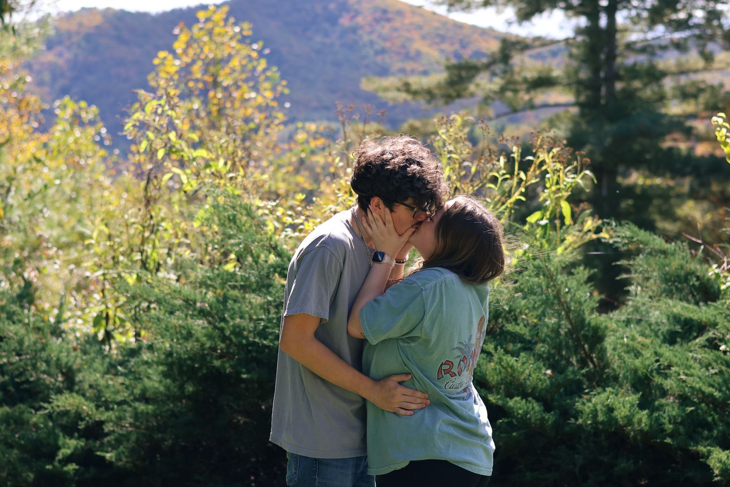 Romantic couple poses together against scenic mountain backdrop with autumn foliage.