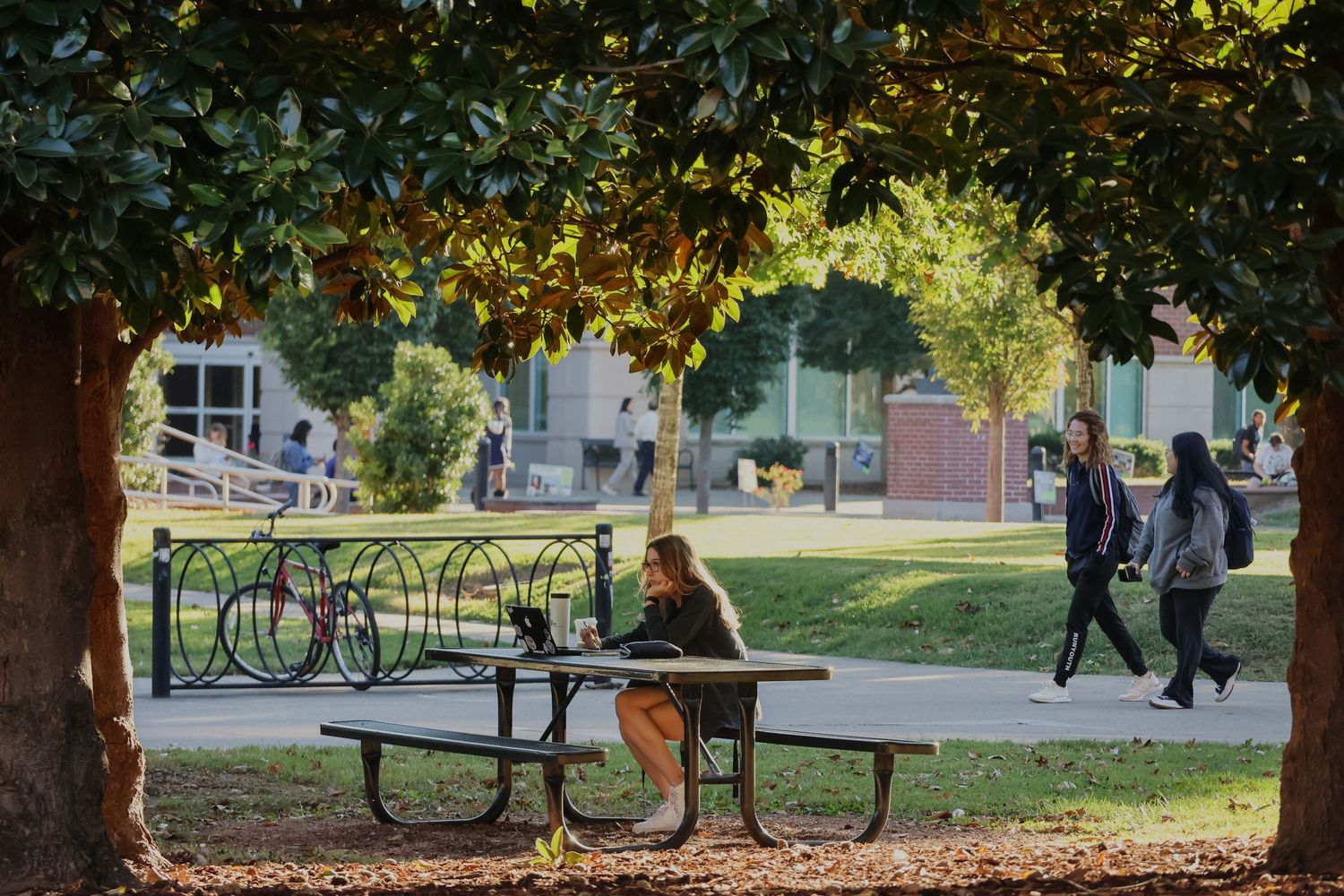Digital photograph of a young adult (female) sitting on a bench outside.