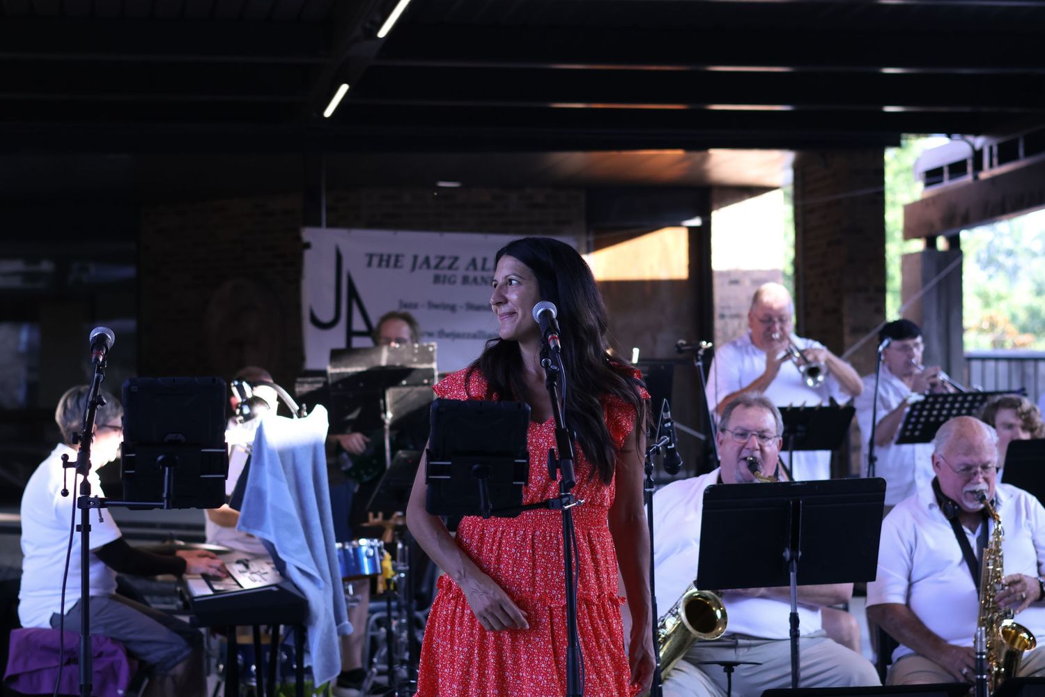Jazz band performing on stage with musicians playing instruments under dim lighting.