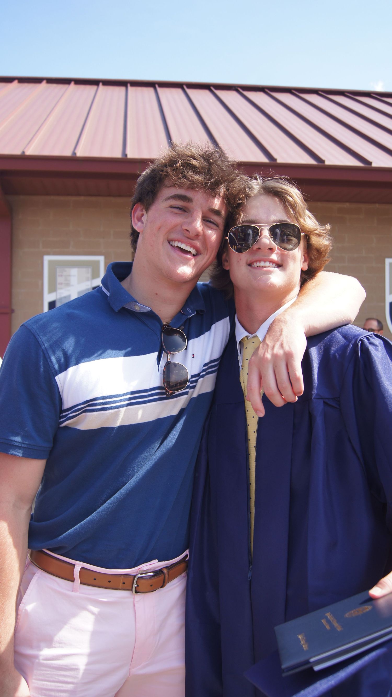 Two graduates in blue and white attire share a celebratory moment during graduation day.