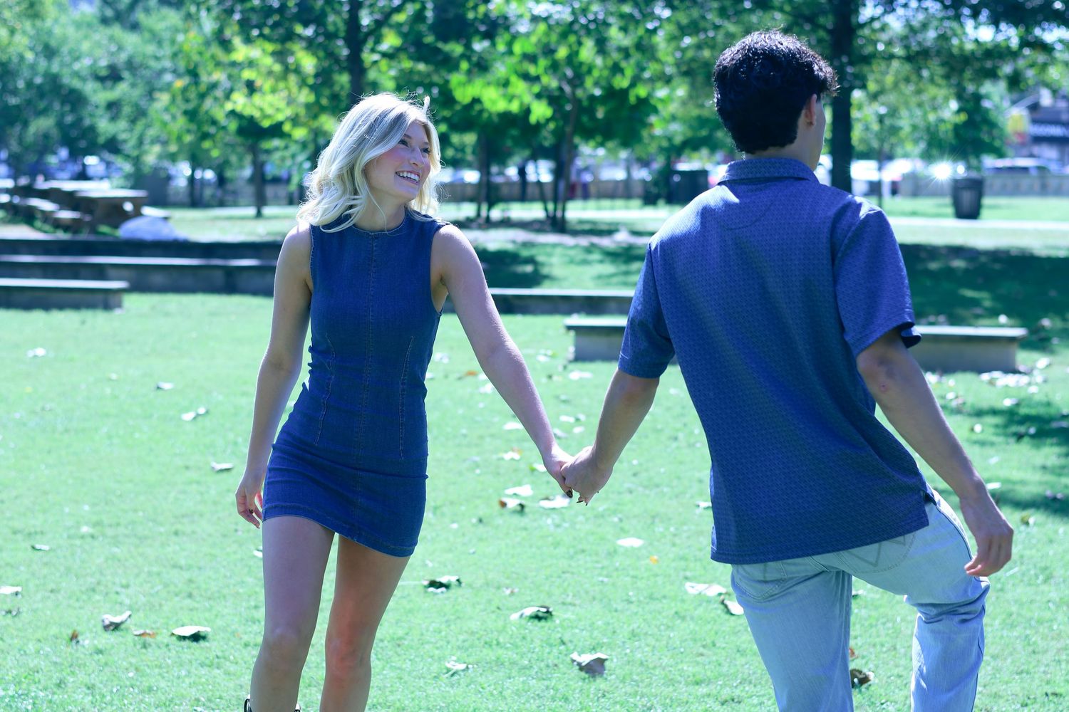 People in coordinating blue outfits walking through green park grounds.