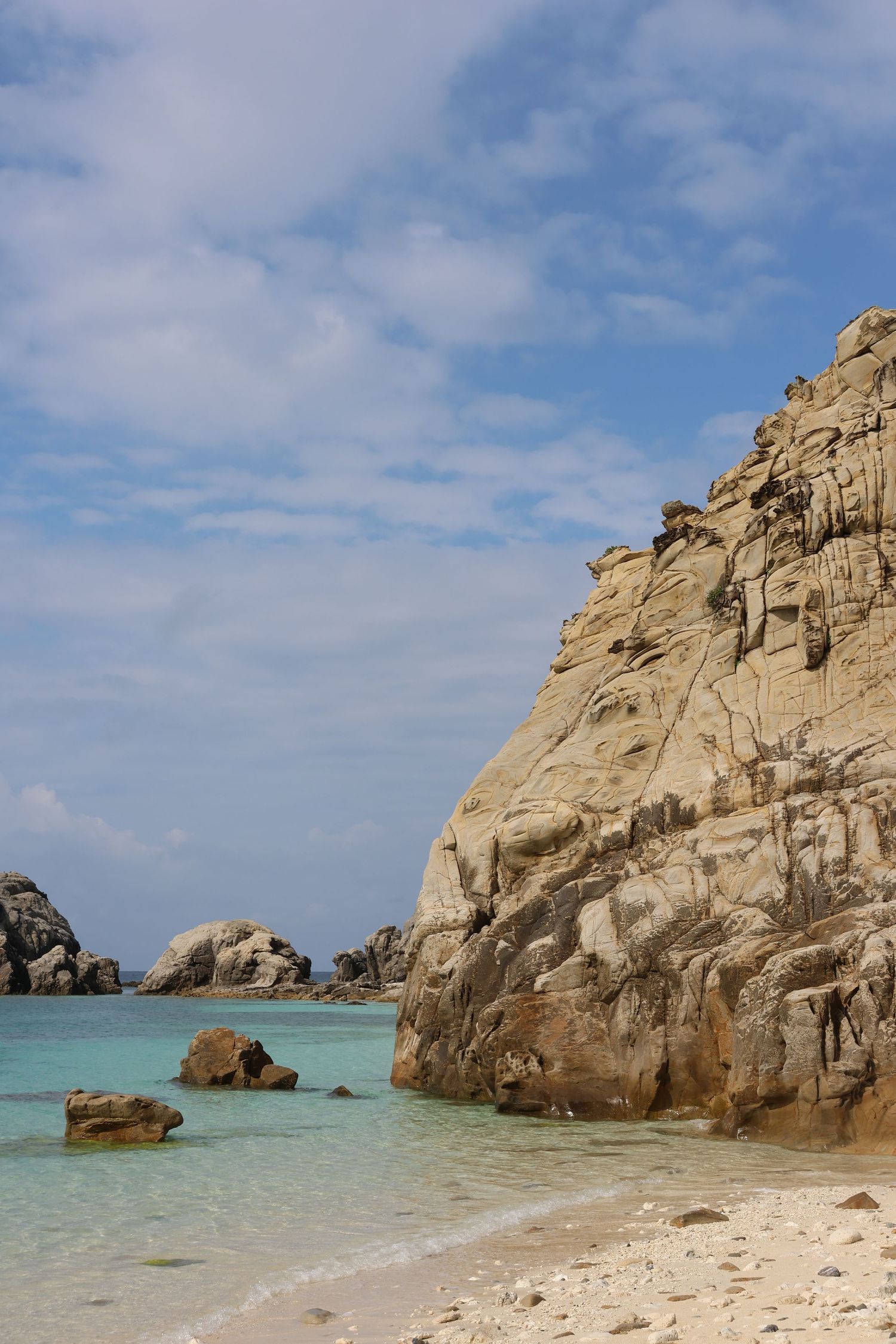 Pristine Japan beach with crystal clear turquoise water and large rocky cliffs.