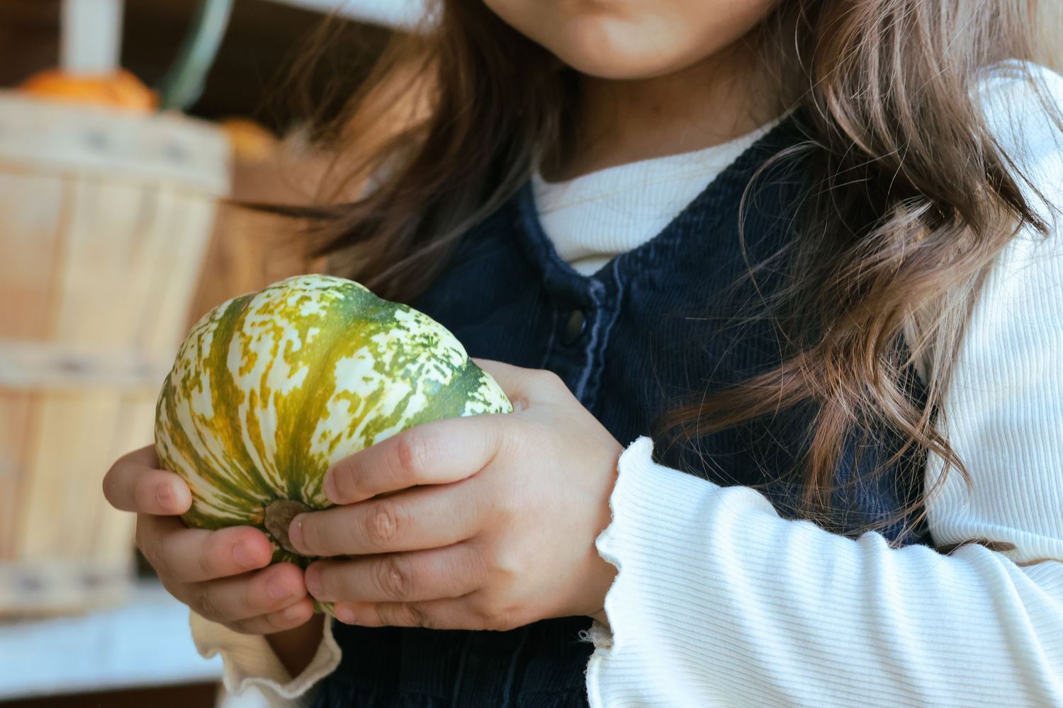Digital photograph of a young girl holding a pumpkin.