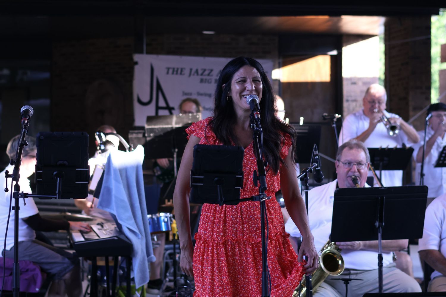 Musicians perform on outdoor stage during daytime event.