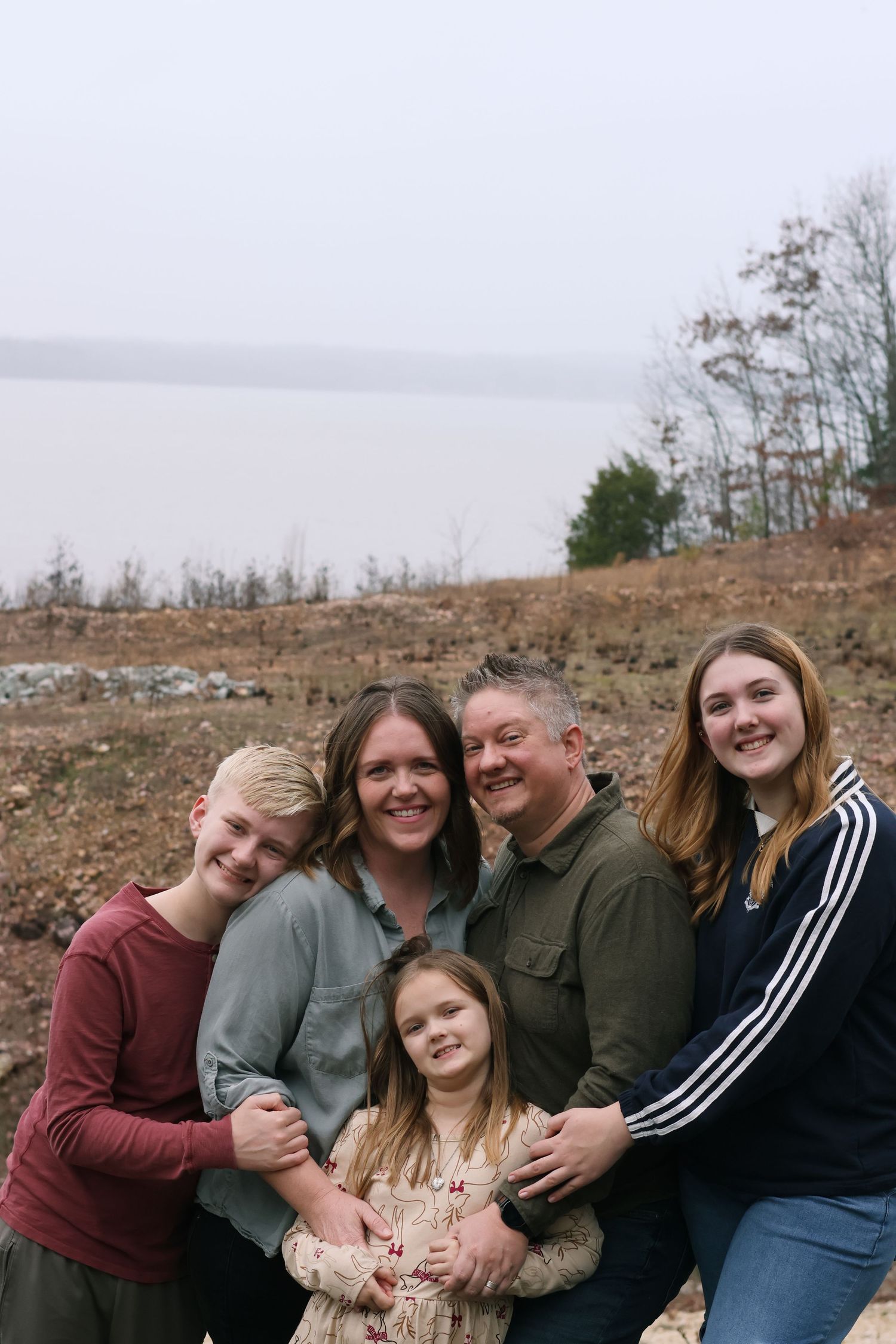 A group of people sitting together outdoors on a cloudy day for a casual family portrait.