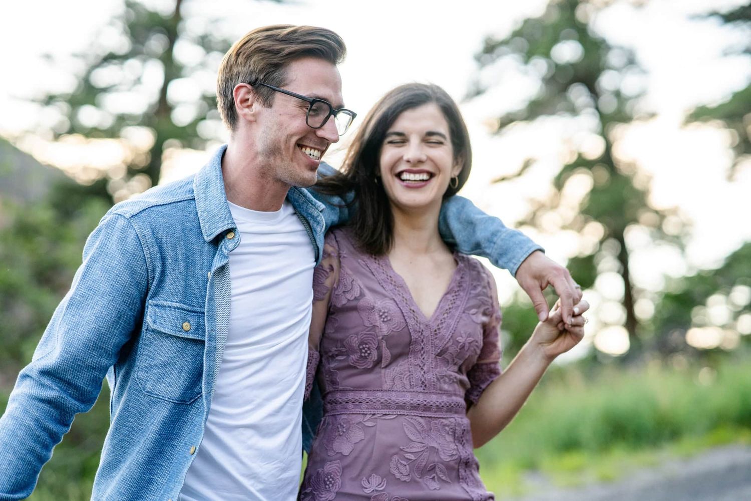 A couple sharing laughter while walking outdoors in casual attire.