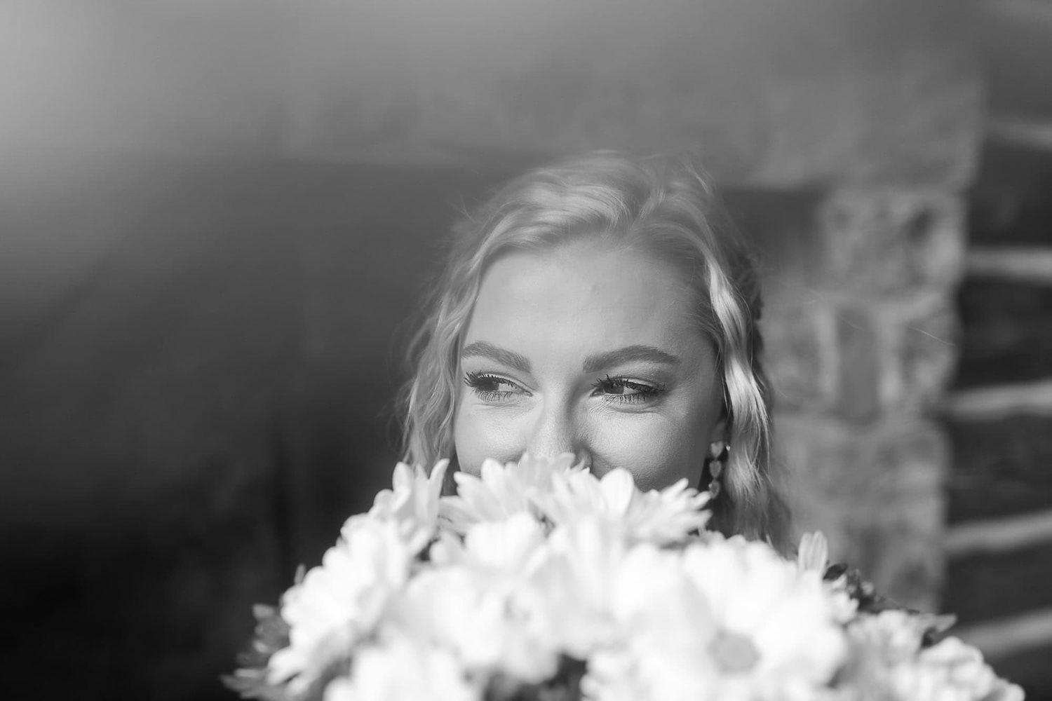 A close-up black and white portrait with flowers in soft focus.