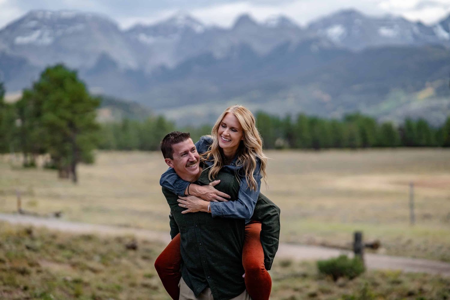 Couples shares piggy back ride at Top of the Pines. Captured by Ridgway Colorado Family photographer