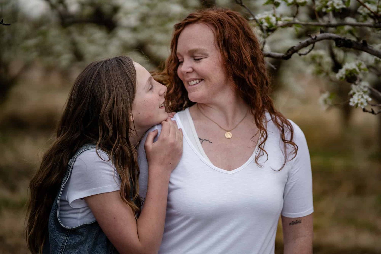 Joyful mother and daughter sharing a tender moment among spring blossoms.