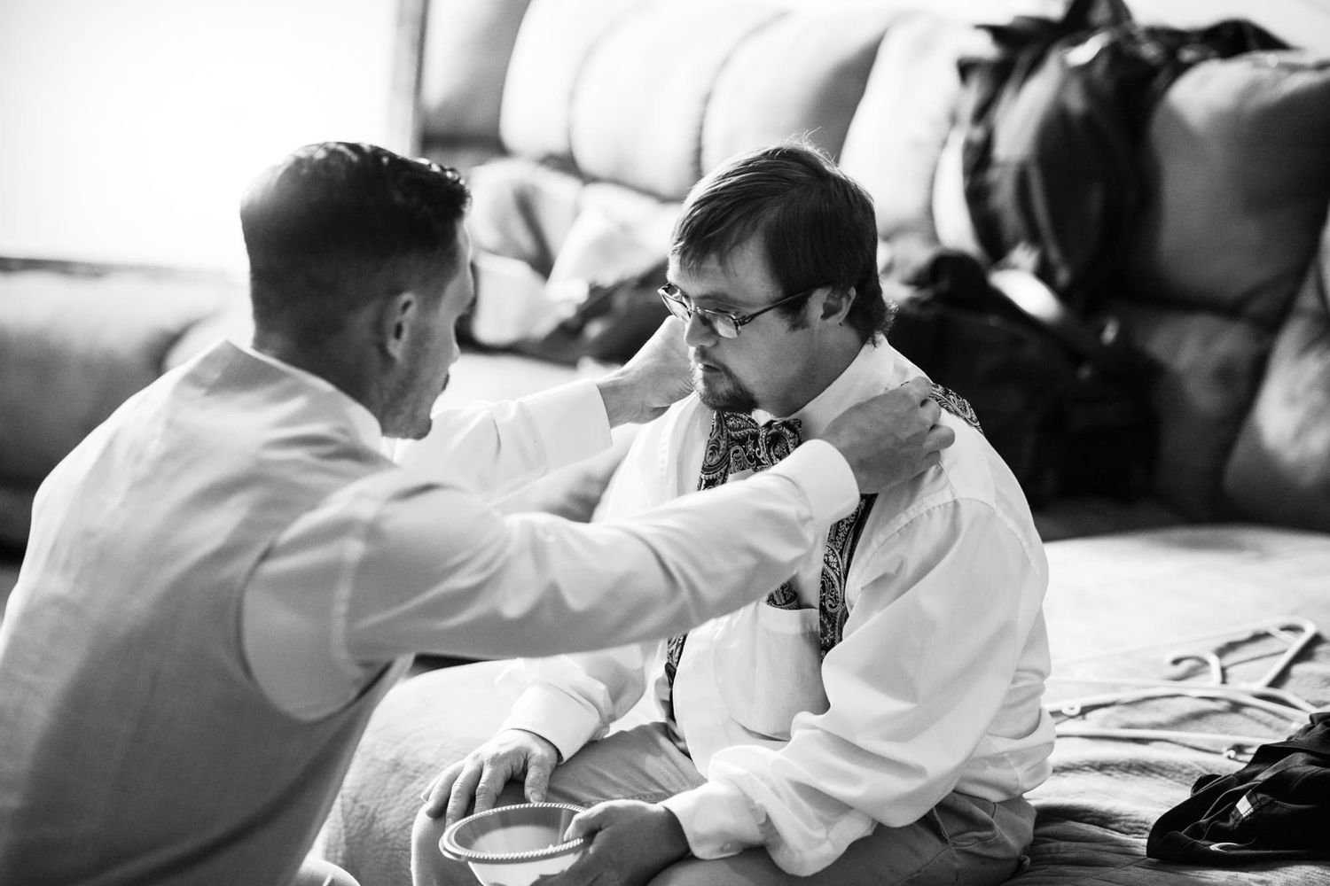 Black and white intimate moment of pre-wedding preparation indoors.