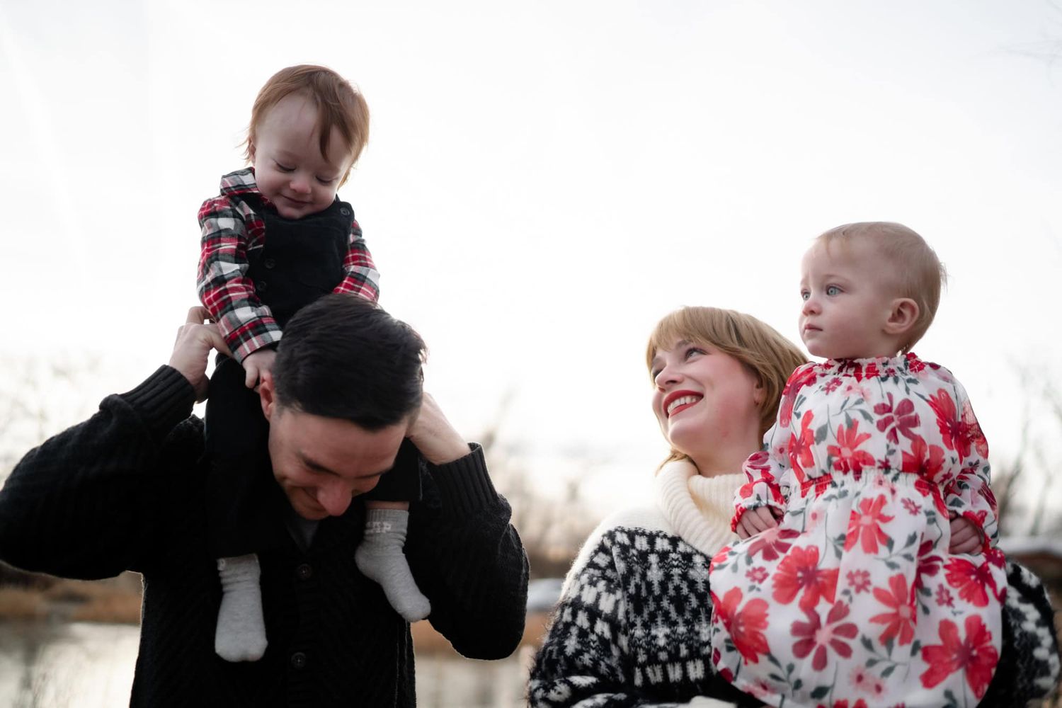 A joyful family moment as a child rides on shoulders while others laugh.