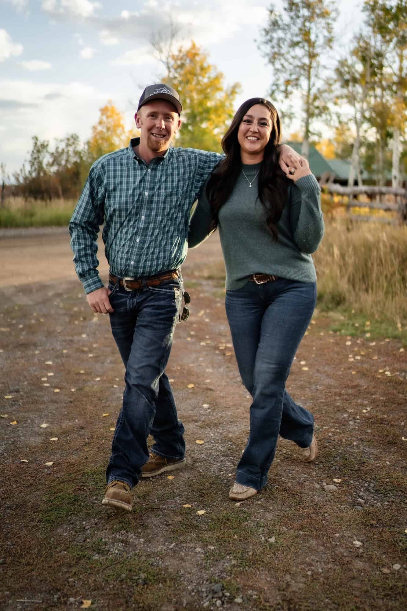 Couple walking together outdoors on dirt path during autumn sunset.